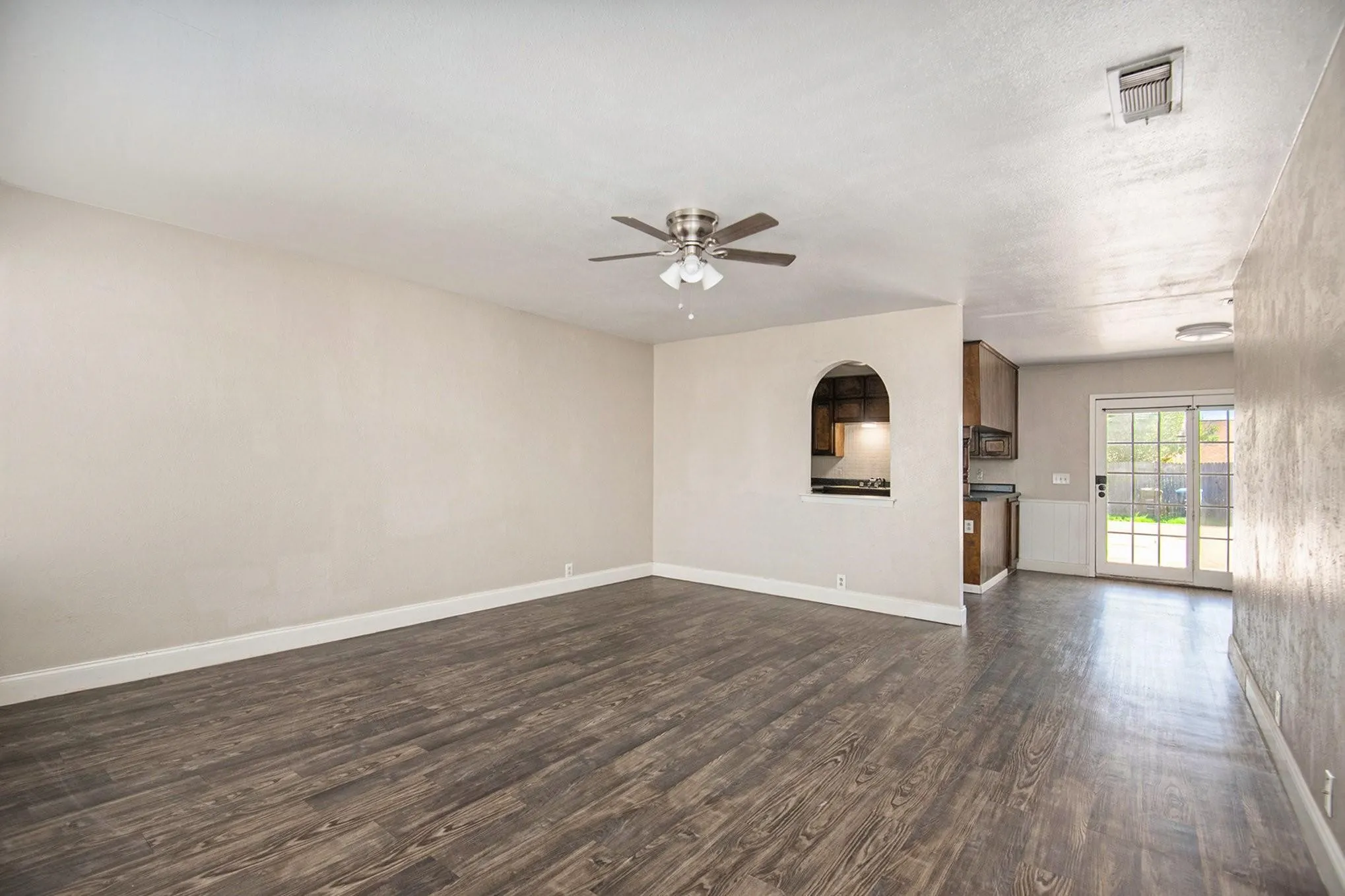 Spacious room featuring wood-finish flooring, a contemporary ceiling fan, and light-toned walls