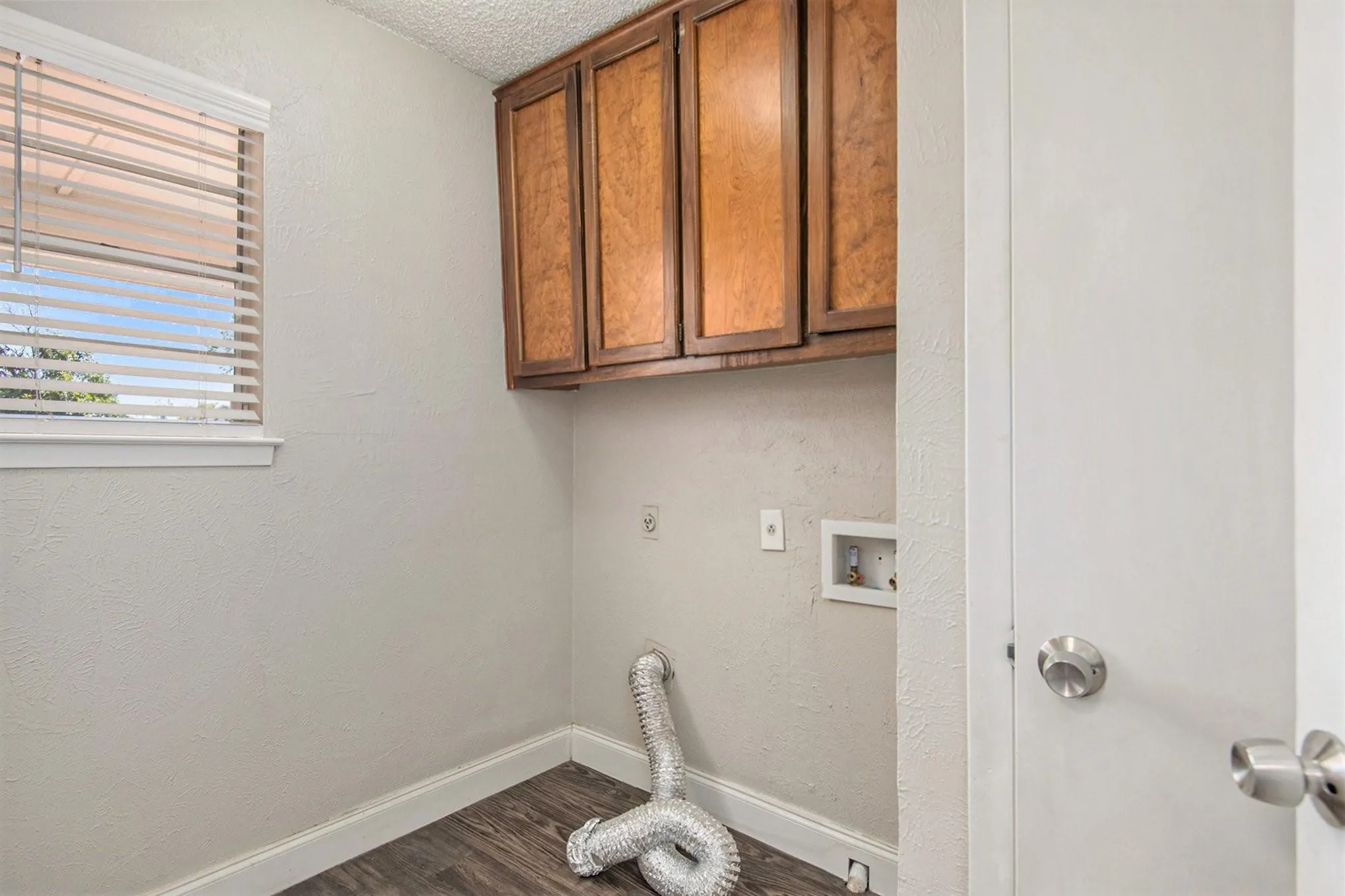 Dedicated utility space featuring wood-finish flooring and neutral wall tones
