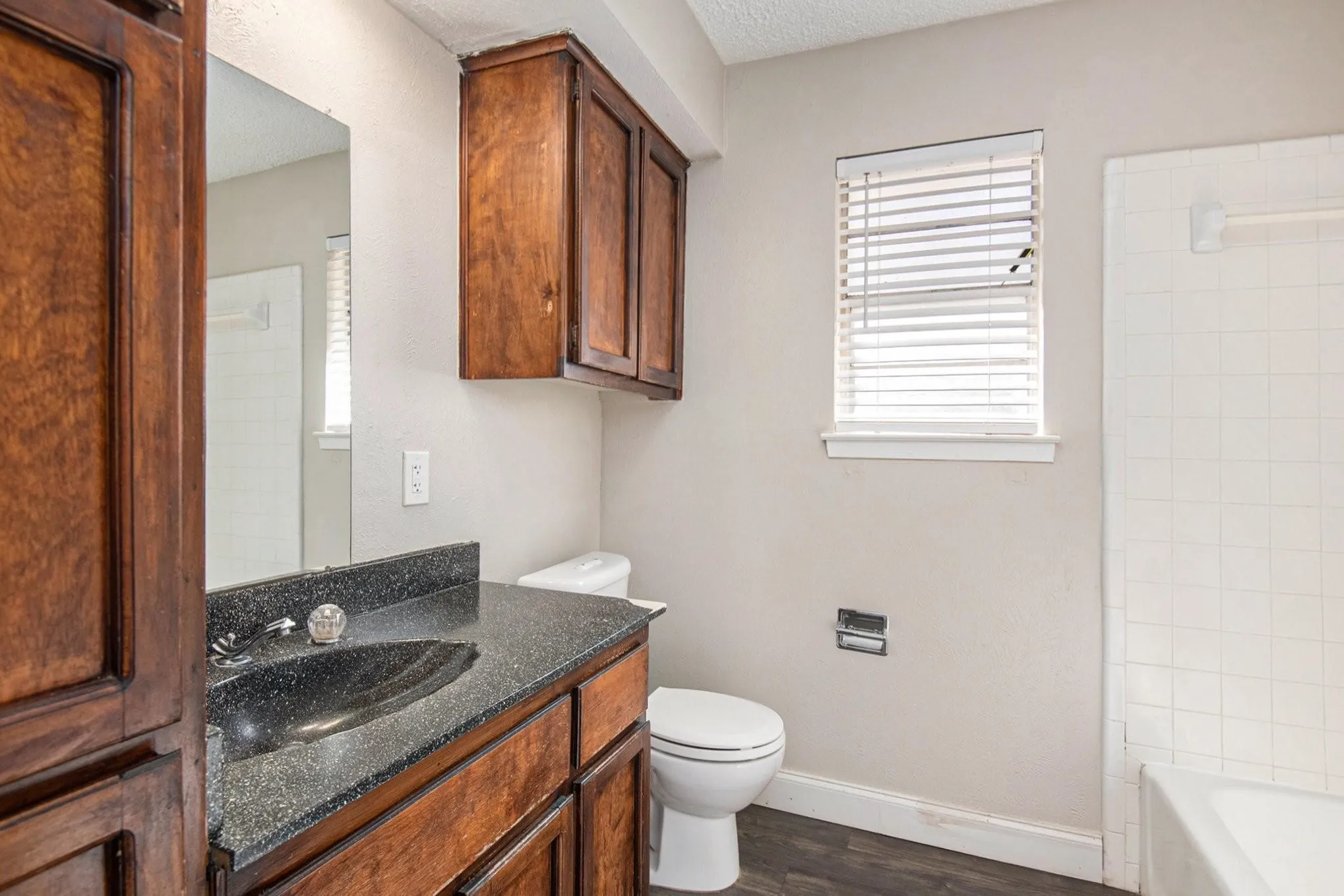 Bathroom featuring a dark wood-finish vanity with an integrated basin and a speckled countertop