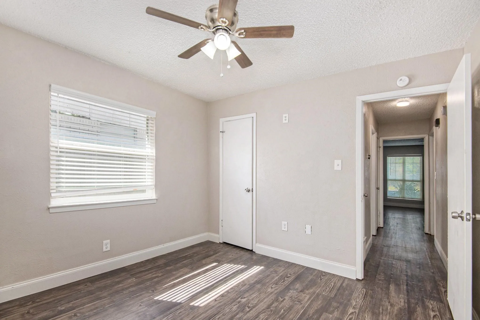 Interior room featuring wood-finish flooring, light neutral paint, and white baseboards
