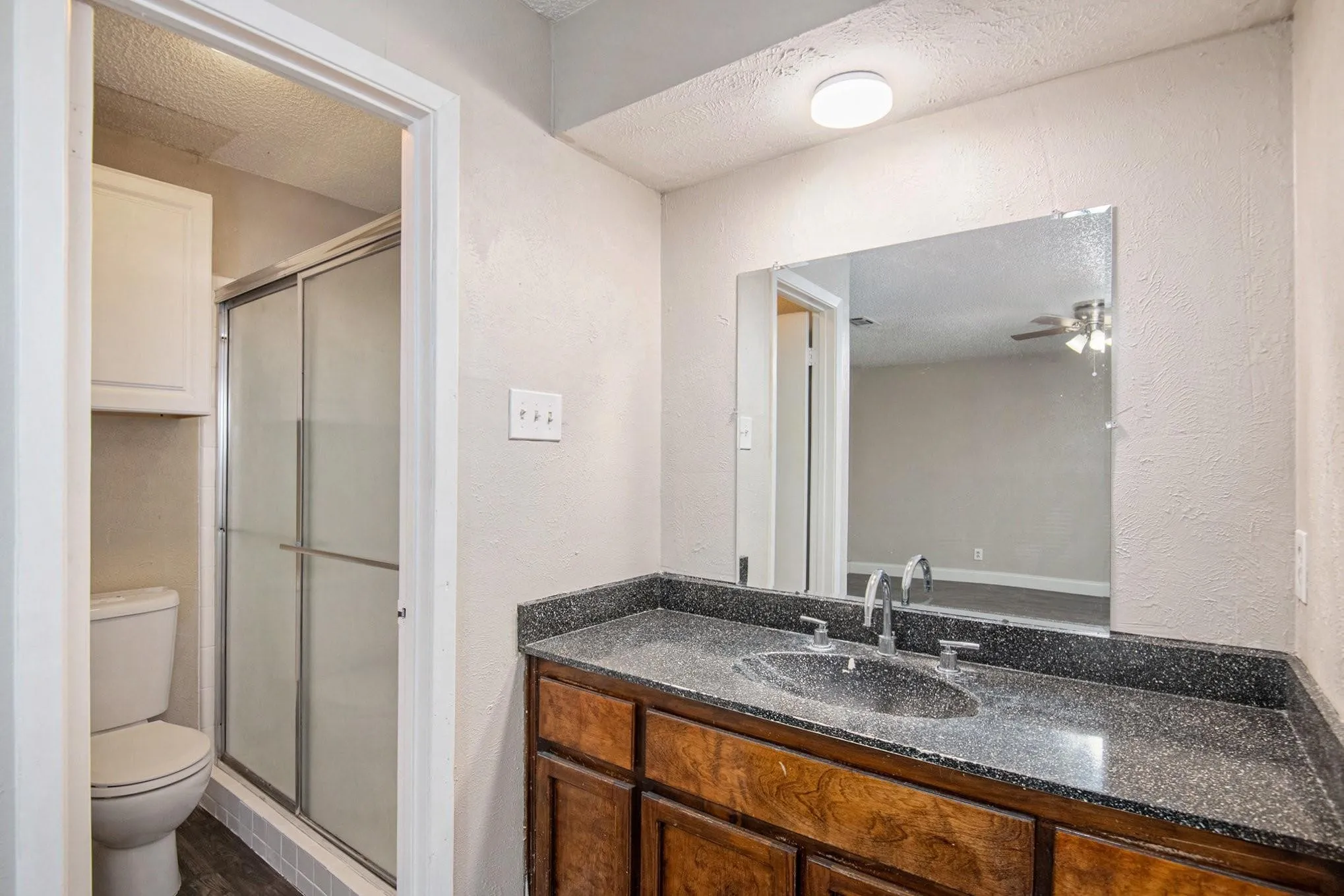 Bathroom vanity with a dark wood-finish cabinet and a speckled countertop