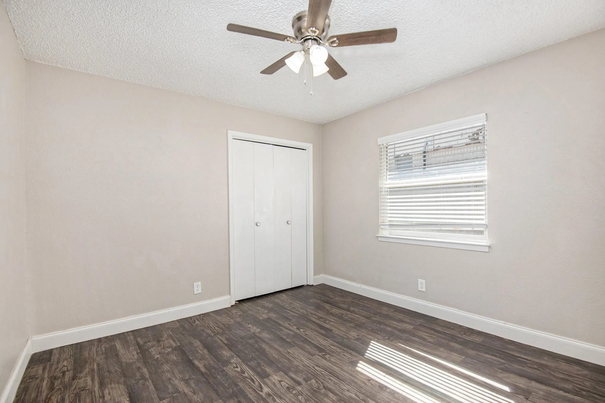 Room featuring wood-finish flooring, neutral wall tones, and white baseboards