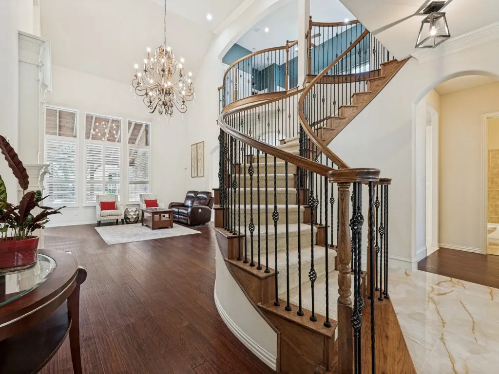 Grand curved staircase with wrought iron balusters and carpeted treads