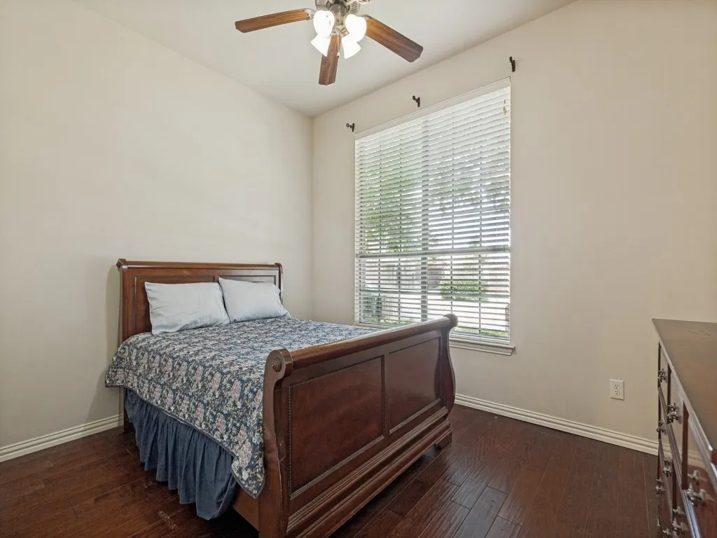 Interior space featuring rich wood-finish flooring, a ceiling fan with integrated lighting, and a window with blinds