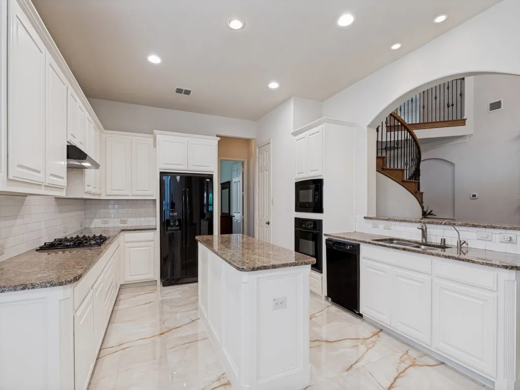 Kitchen featuring white cabinetry, stone countertops, a central island, integrated appliances, and recessed lighting