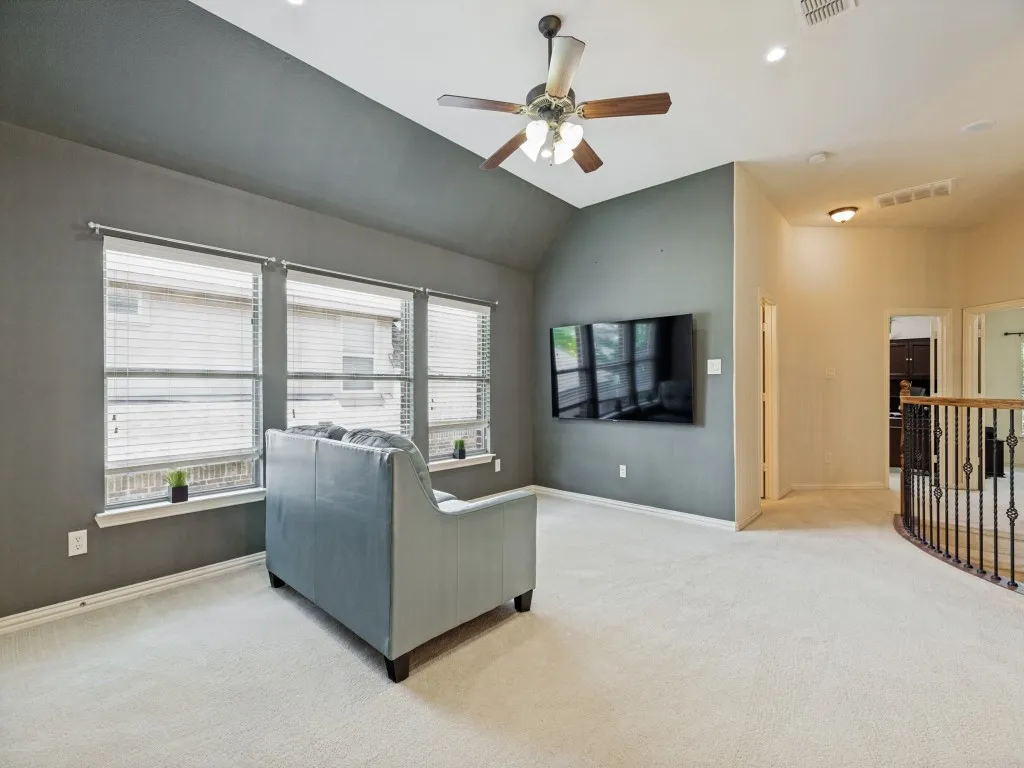 Spacious room featuring vaulted ceilings, neutral carpeting, and a ceiling fan