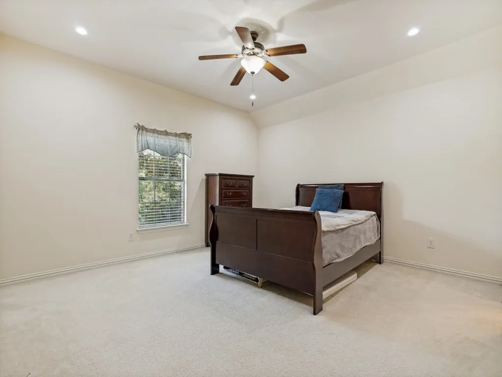 Bedroom featuring sloped ceilings with recessed lighting, a ceiling fan with light fixture, light neutral-toned walls, and plush carpeting