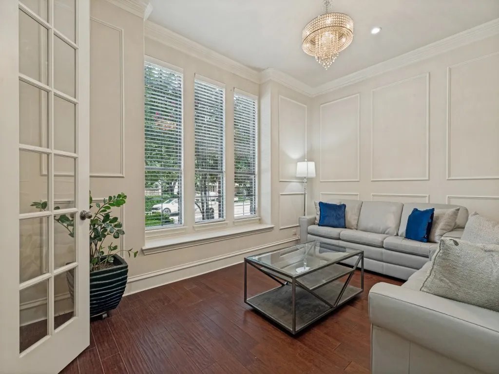 Hardwood flooring with a crystal chandelier and detailed wall molding