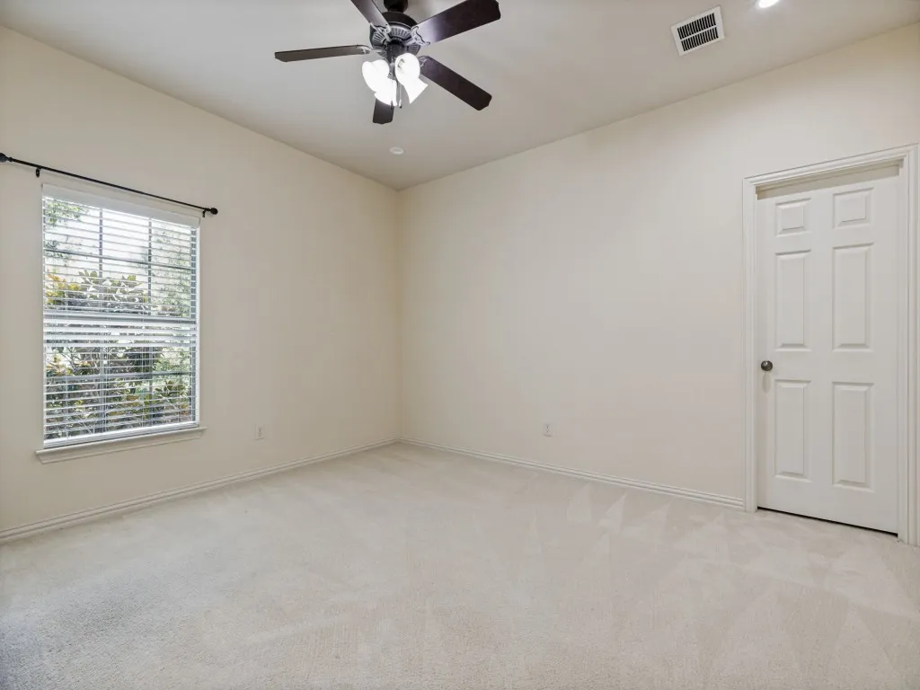 Spacious room featuring vaulted ceilings, plush carpeting, a large window with horizontal blinds, a ceiling fan with integrated lighting, and a paneled interior door