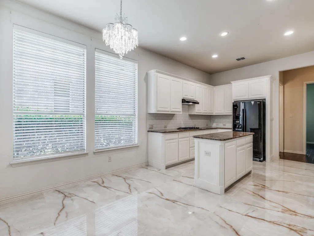 Gourmet kitchen and dining area featuring a crystal chandelier, recessed lighting, white cabinetry, a kitchen island with stone countertop, and wood-finish flooring