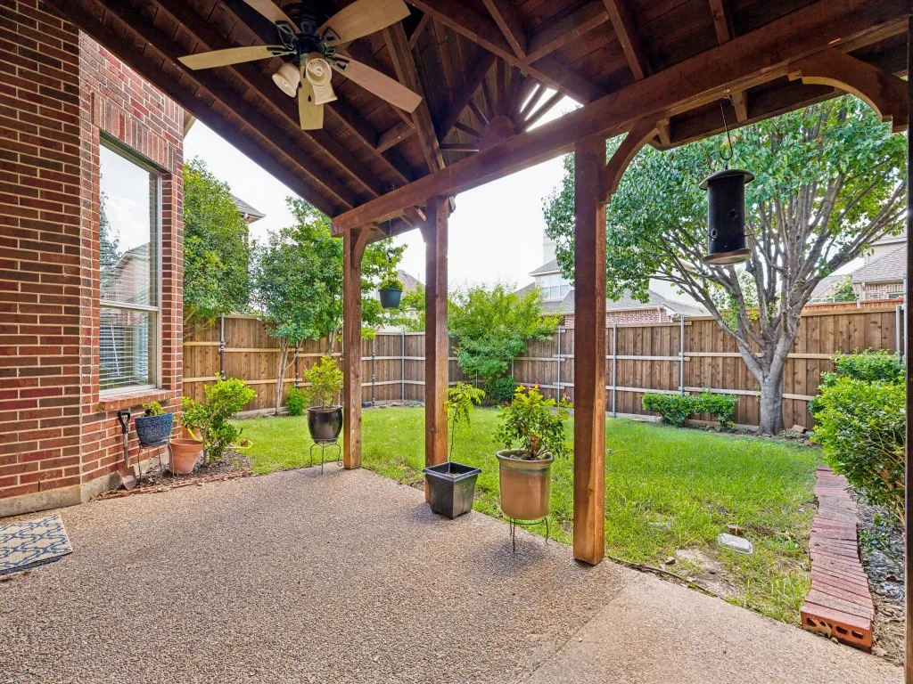 Covered patio featuring an exposed aggregate concrete surface, a wood-finish ceiling with a mounted fan, and substantial wood-finish support beams