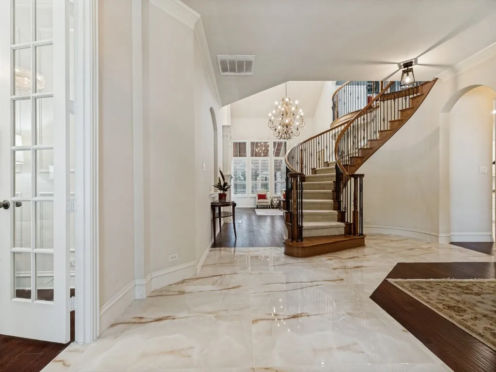 Grand entry featuring a curved wood staircase with wrought iron balusters and carpeted treads