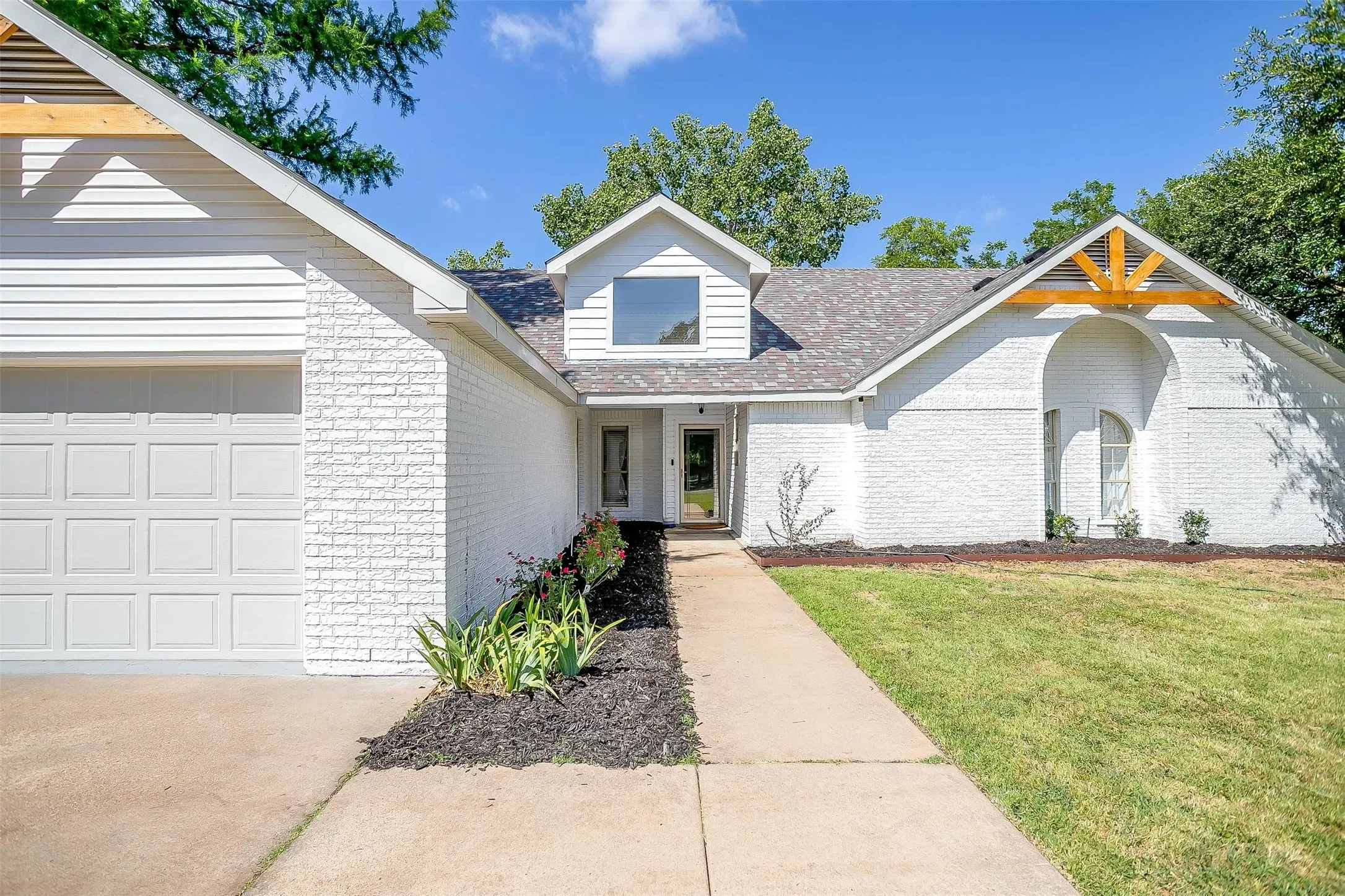 White painted brick exterior with siding accents and a contrasting dark roof