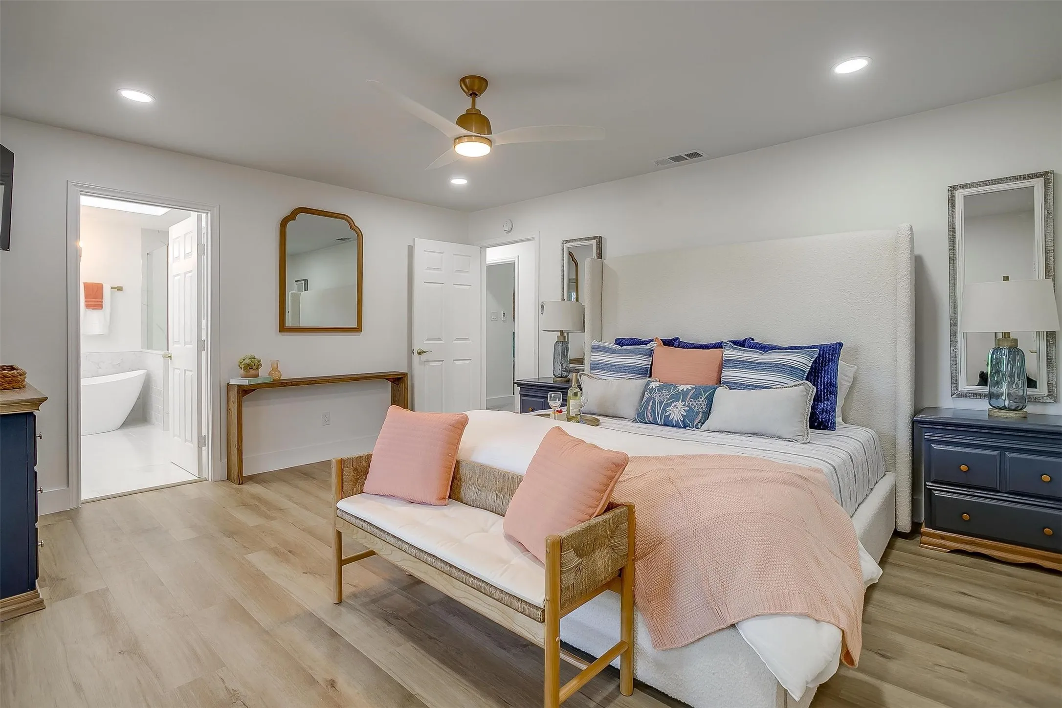 Spacious bedroom featuring light wood-finish flooring, recessed lighting, and a ceiling fan with integrated illumination