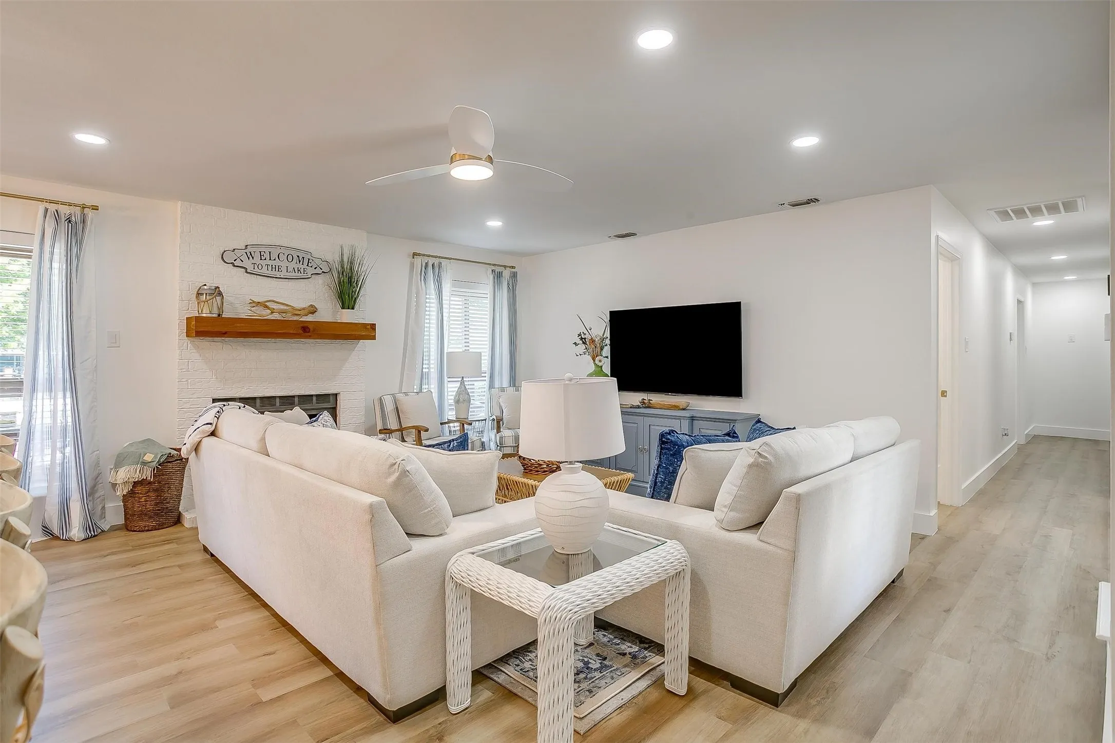 Spacious living area featuring light wood-finish flooring, recessed lighting, and a modern ceiling fan