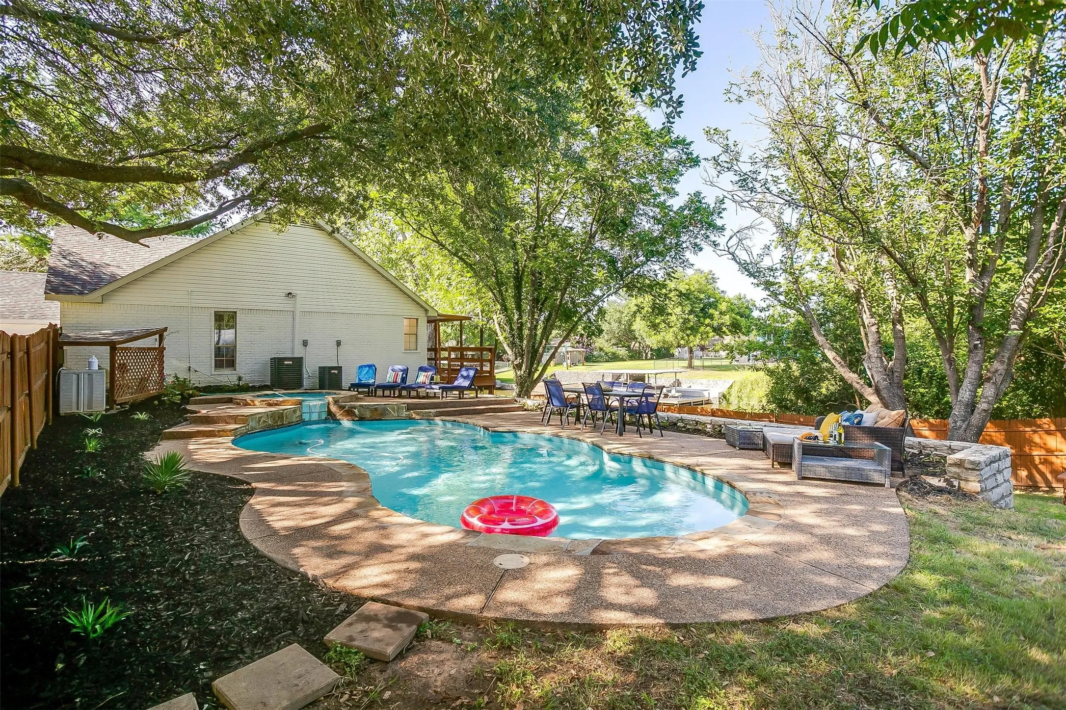Freeform swimming pool with a rock waterfall feature and surrounding aggregate concrete patio