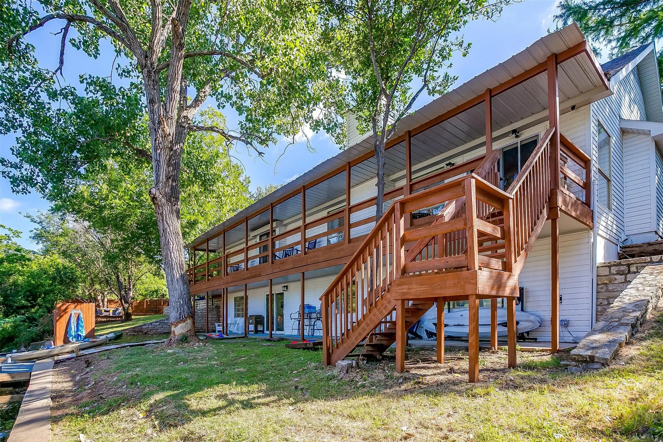 Multi-level outdoor living featuring a wood-finish deck, covered patio, and exterior staircase