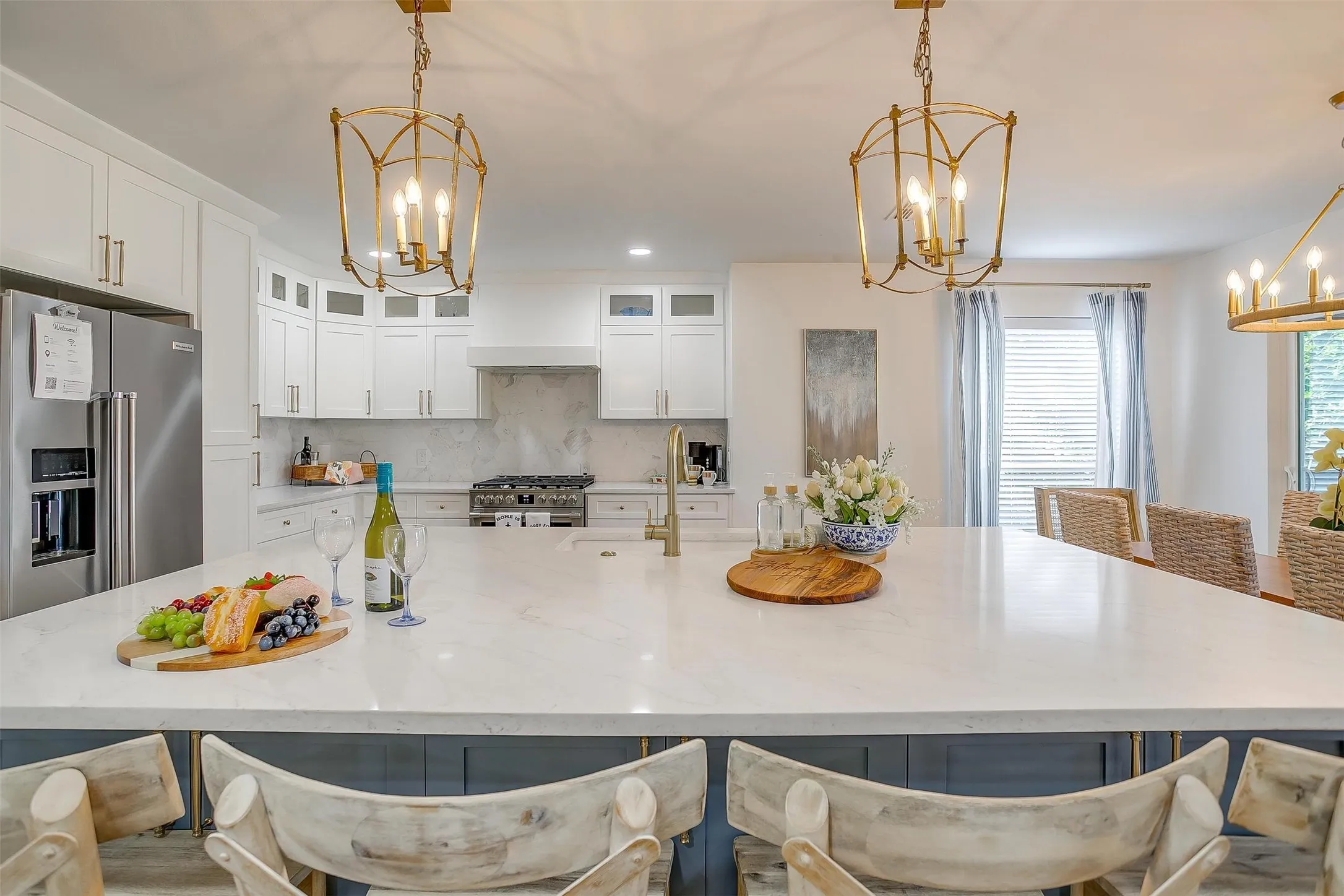 Spacious kitchen island featuring a light-toned countertop, integrated sink with brass-finish faucet, and two decorative brass-finish pendant lights