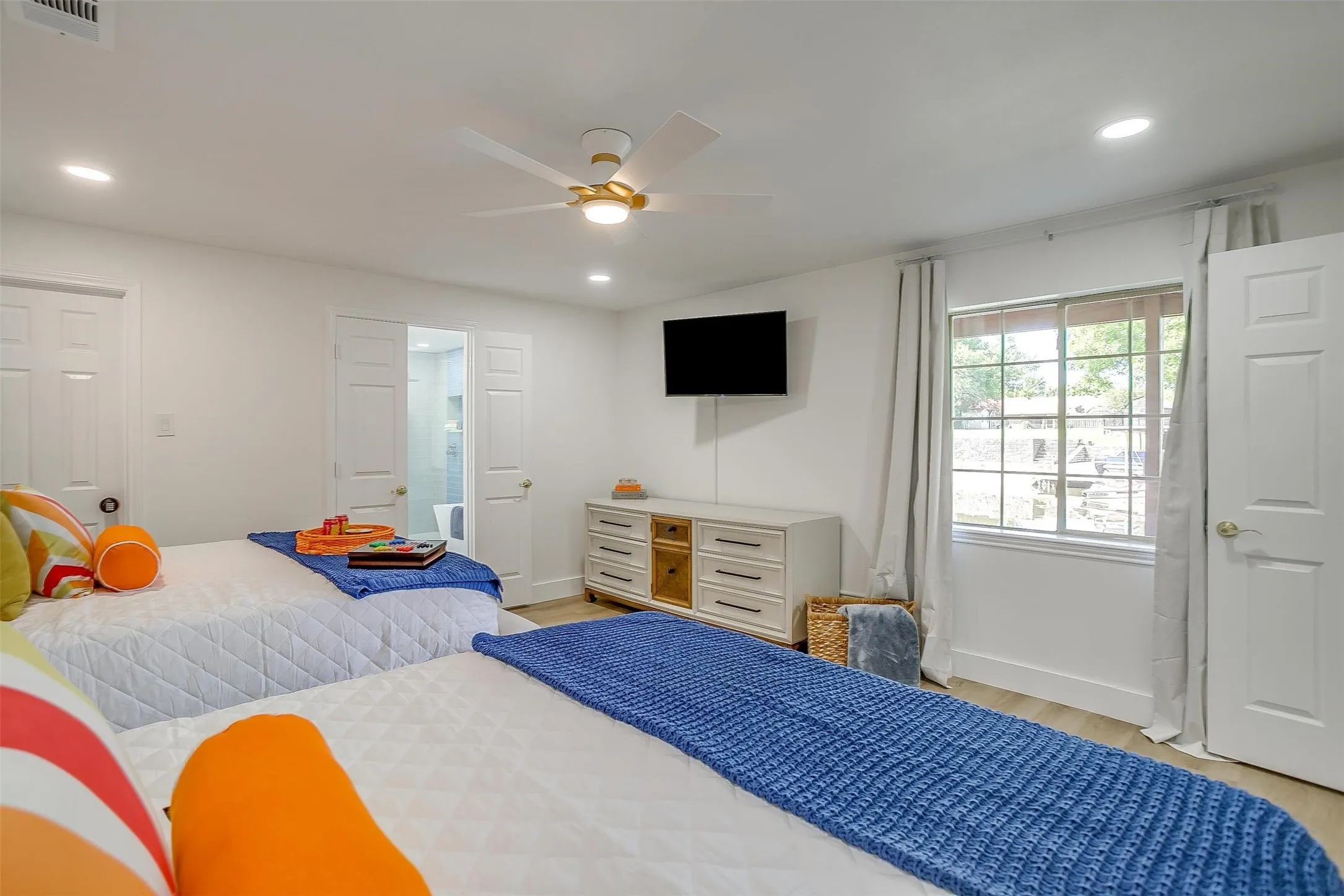 Spacious room featuring light wood-finish flooring, recessed lighting, and a modern ceiling fan