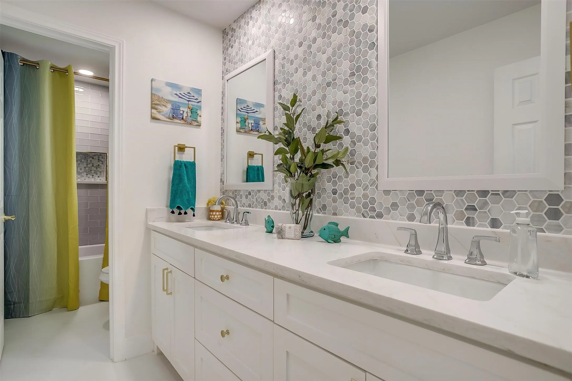Double vanity featuring white cabinetry with gold-tone hardware, rectangular undermount sinks, and polished chrome faucets