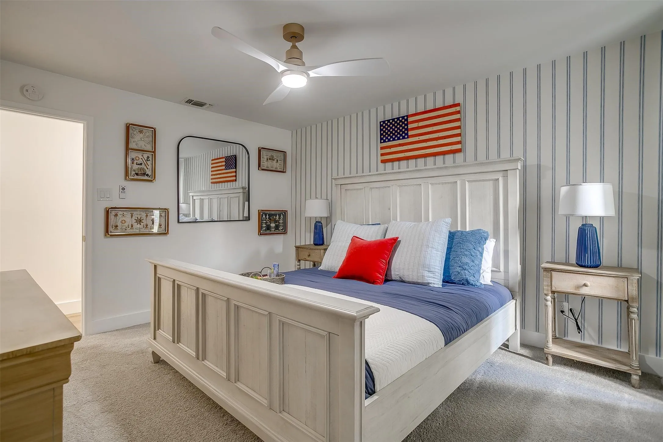 Bedroom featuring a ceiling fan, striped accent wall, and neutral carpeting