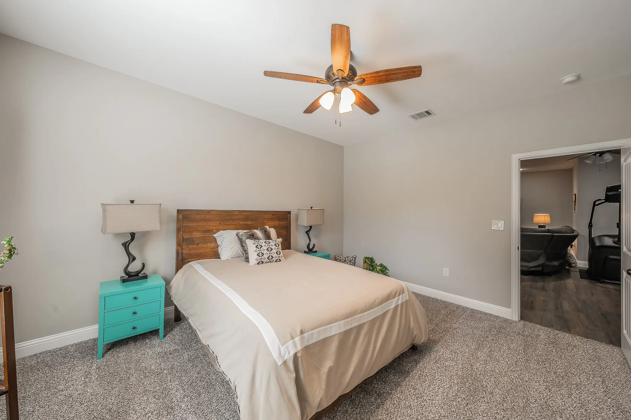 Carpeted room featuring a wood-finish bed frame and a ceiling fan with integrated lighting