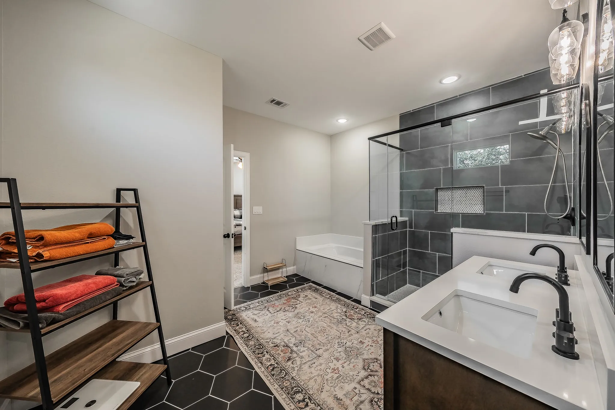 Bathroom featuring hexagon floor tile, a dual vanity with rectangular undermount sinks, and a walk-in shower with dark tile surround and built-in niches