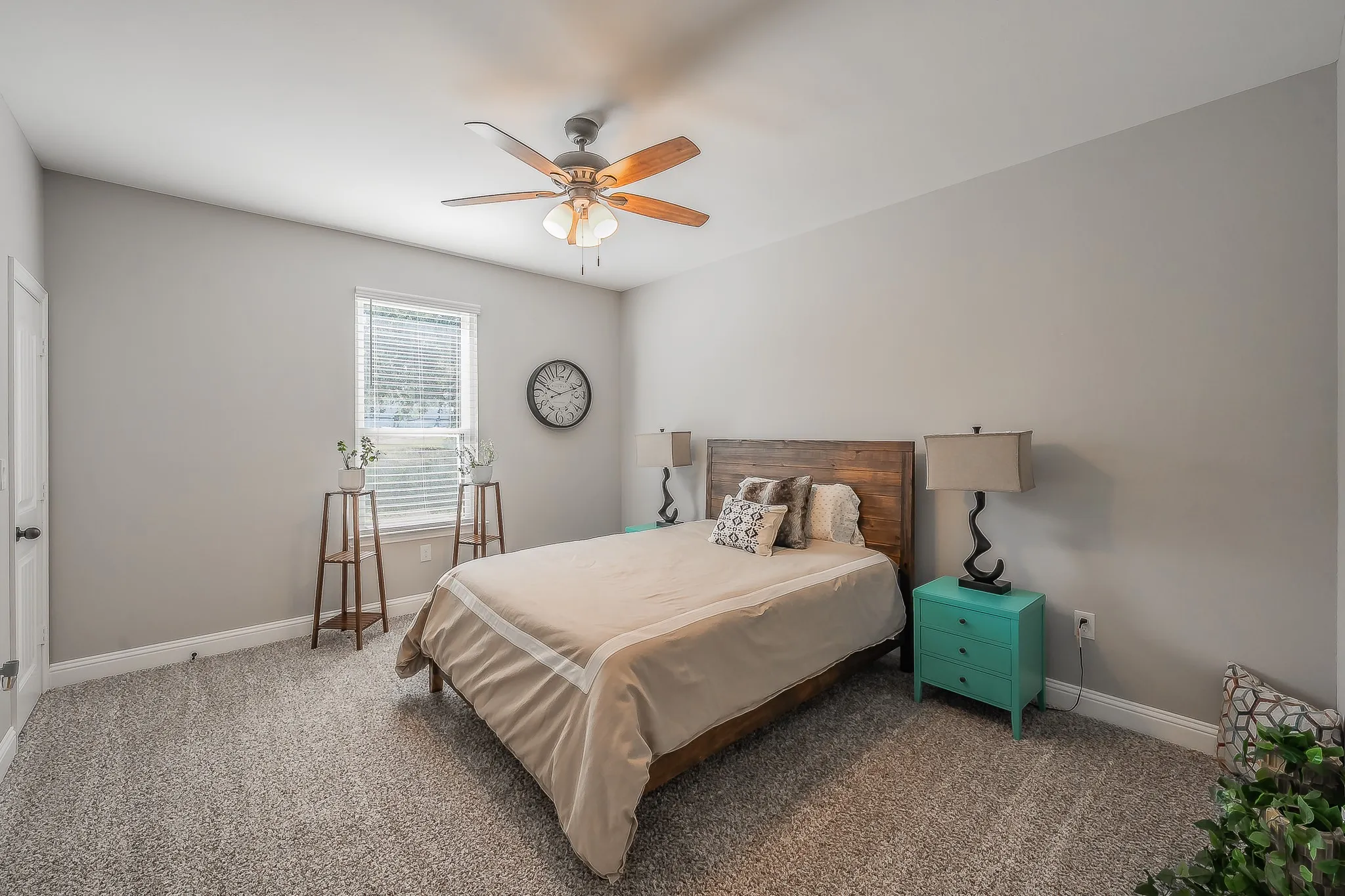 Carpeted room featuring a single window with blinds, a ceiling fan with light fixture, and light gray wall paint