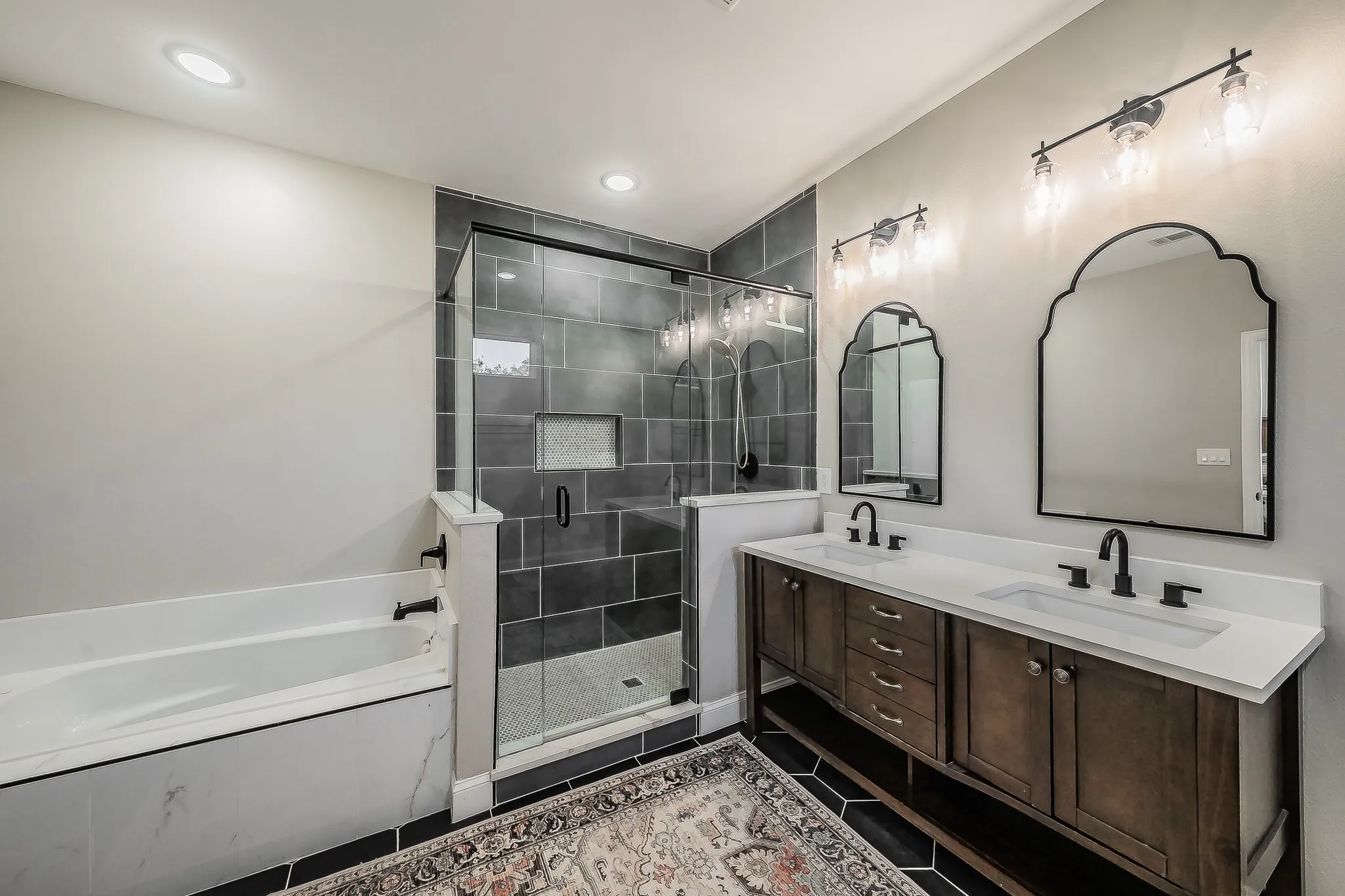 Bathroom featuring a double vanity with dark wood cabinetry, white countertops, and black fixtures