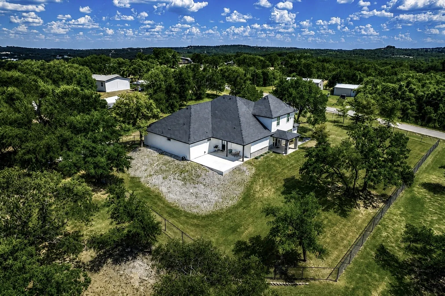 Newly constructed residence featuring a dark shingle roof, white siding, and a covered back patio