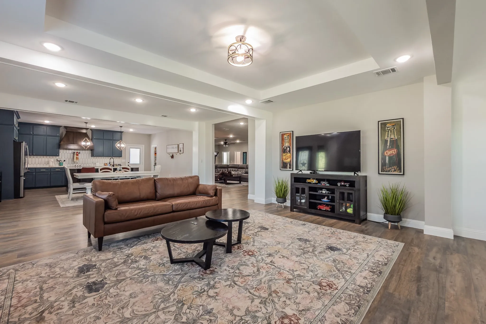 Open-concept living area featuring wood-finish flooring, recessed lighting, and a tray ceiling