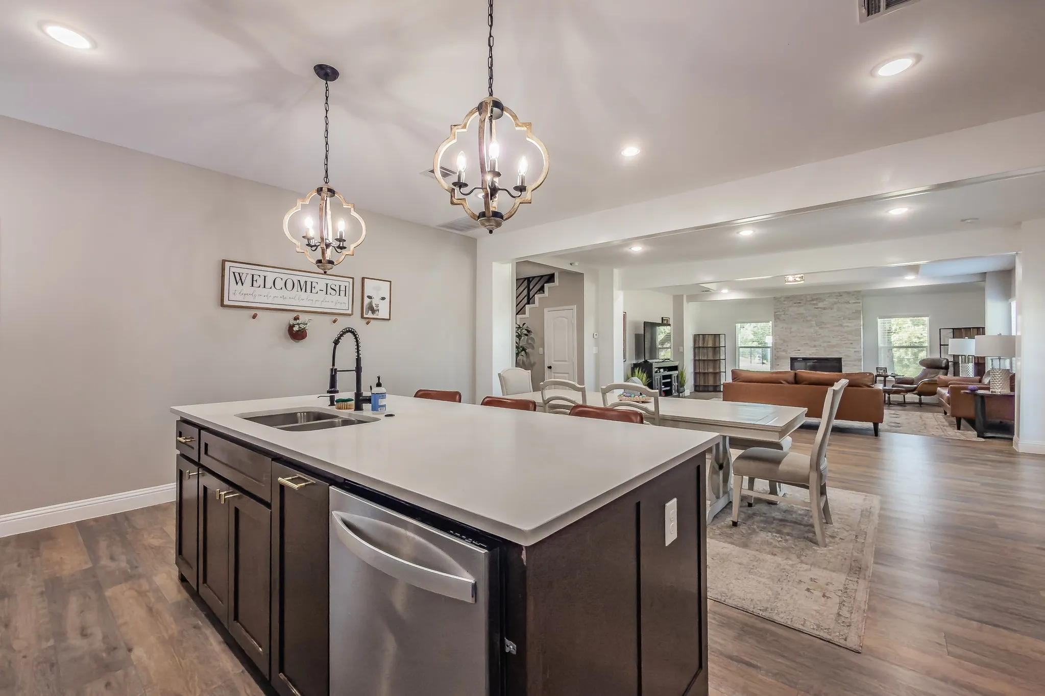 Kitchen island with a double basin sink, stainless steel dishwasher, and a light-toned countertop