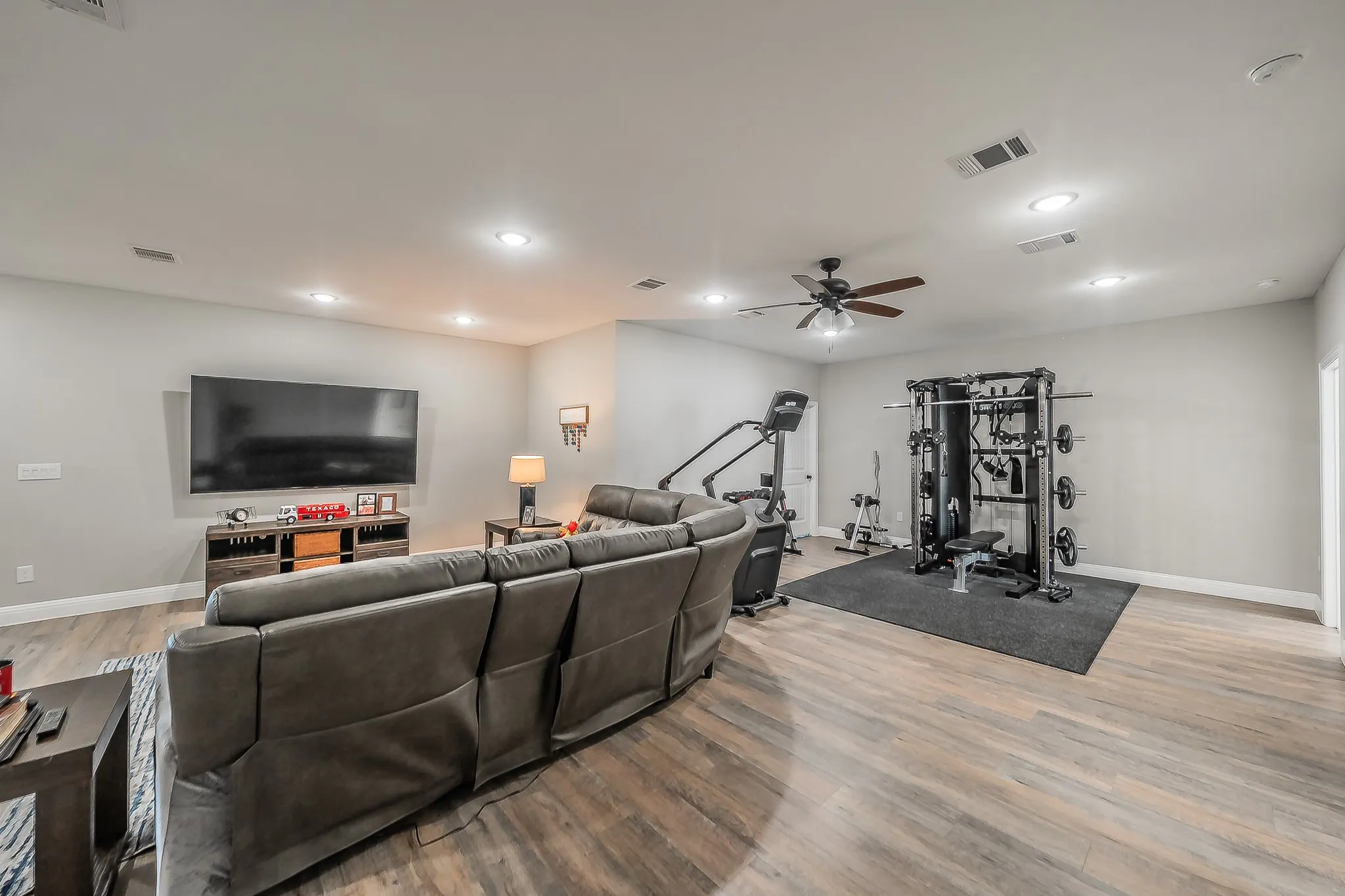 Spacious room featuring wood-finish flooring, recessed lighting, and a ceiling fan