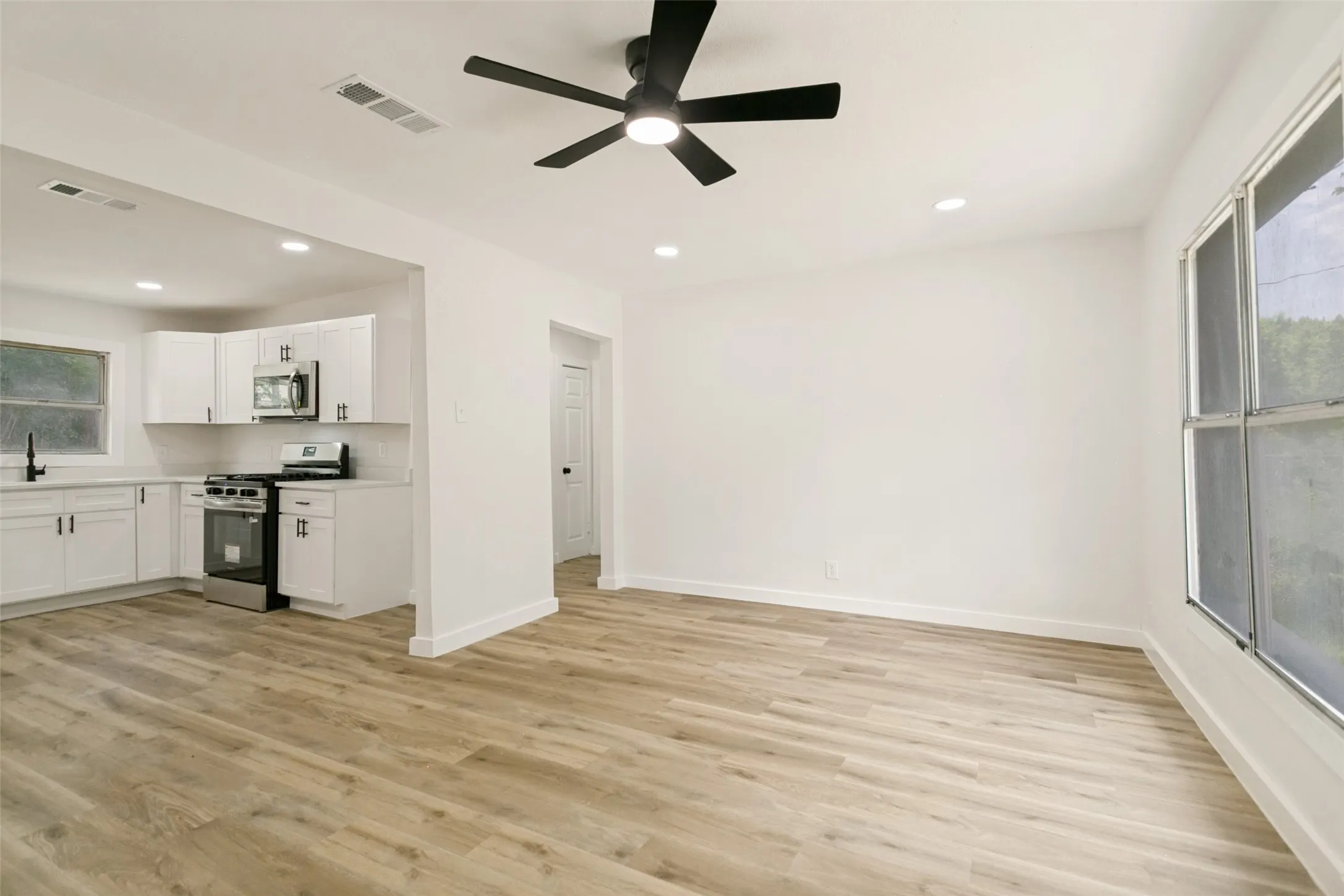 Open-concept living area featuring wood-finish flooring, recessed lighting, and a modern ceiling fan