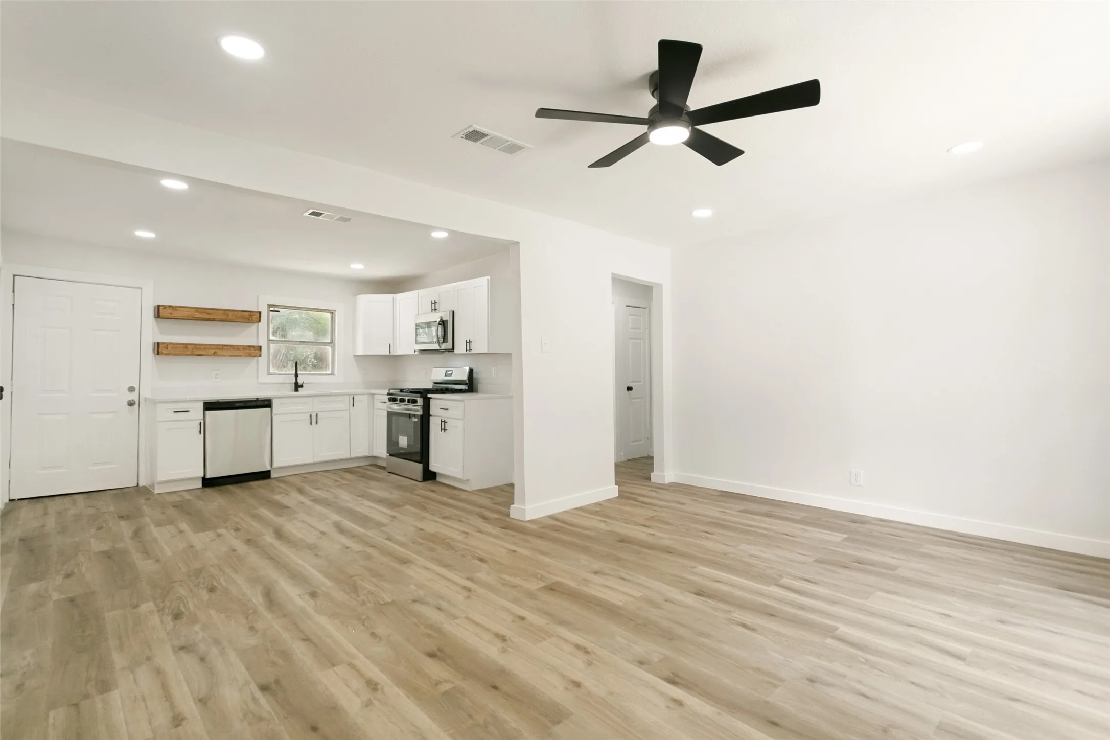 Open-concept living space featuring wood-finish flooring, recessed lighting, and a contemporary ceiling fan