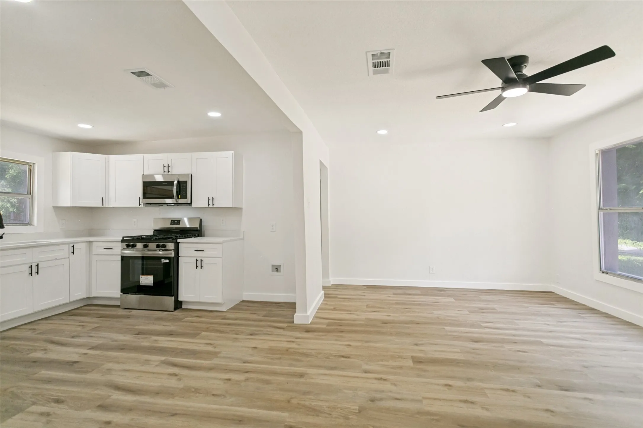 Open-concept living space featuring wood-finish flooring, recessed lighting, and a modern ceiling fan