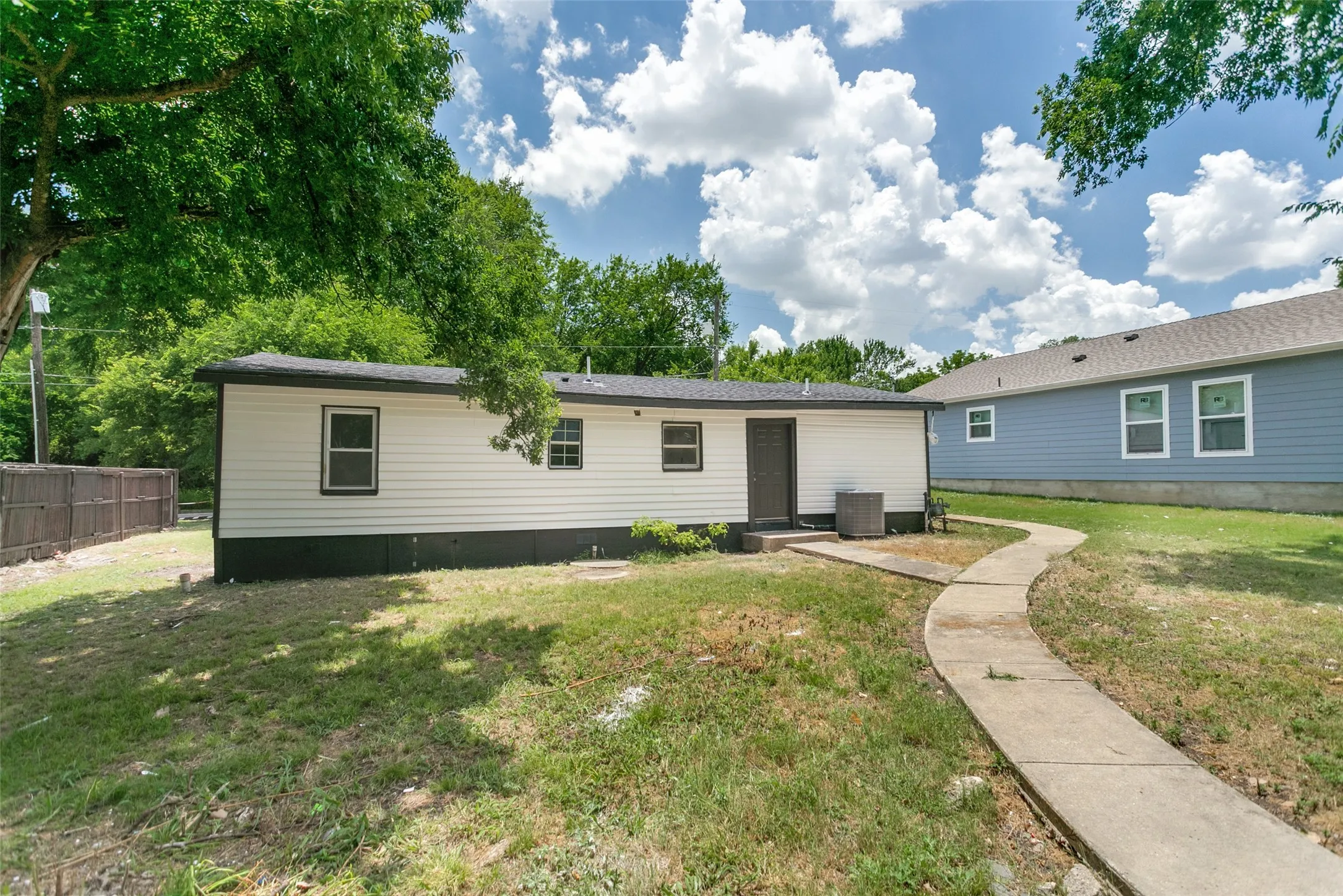 Rear exterior featuring white horizontal siding, a dark trim, and a concrete pathway