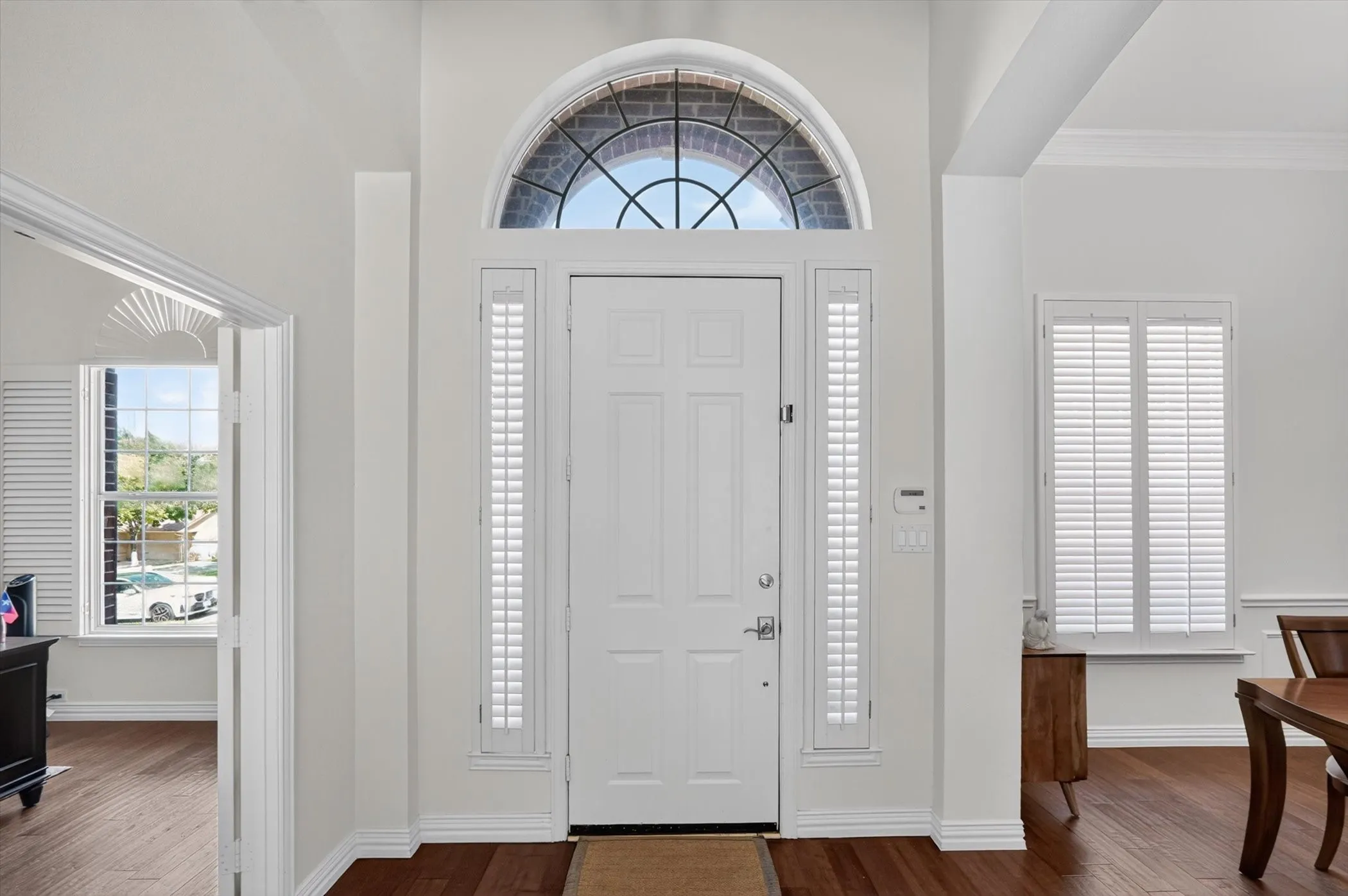 Entryway featuring a paneled door with an arched transom window, side-lites, and wood-finish flooring