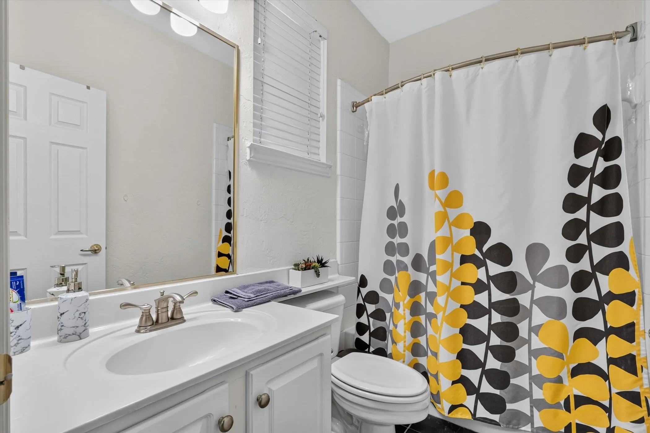 Bathroom featuring a white vanity with integrated sink, brushed nickel faucet, and a large wall mirror