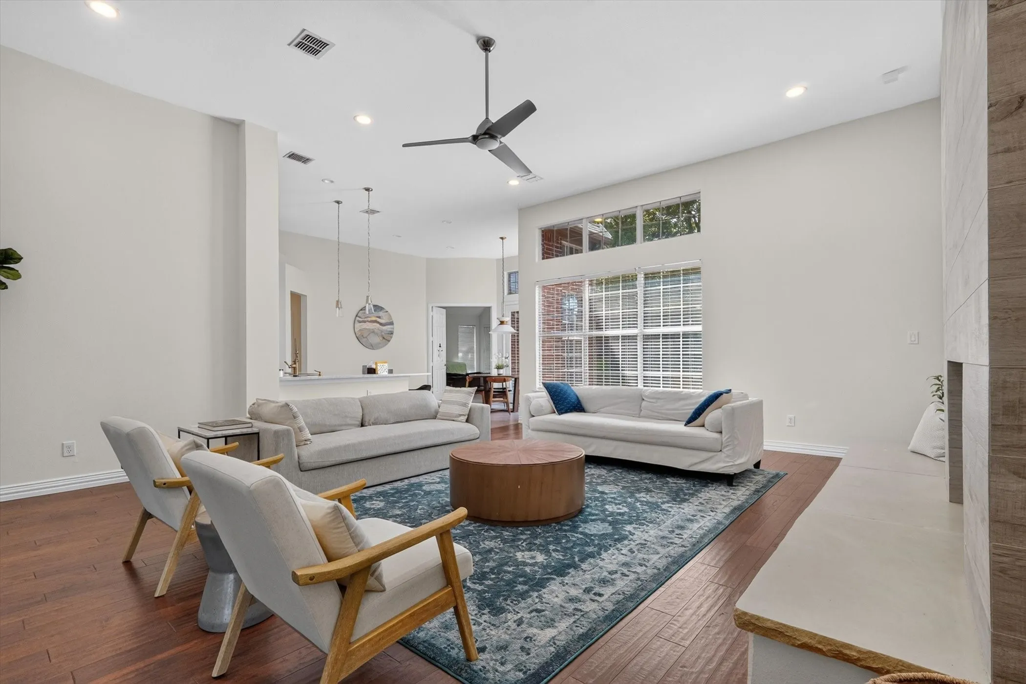Expansive living area featuring high ceilings, wood-finish flooring, recessed lighting, and a modern ceiling fan