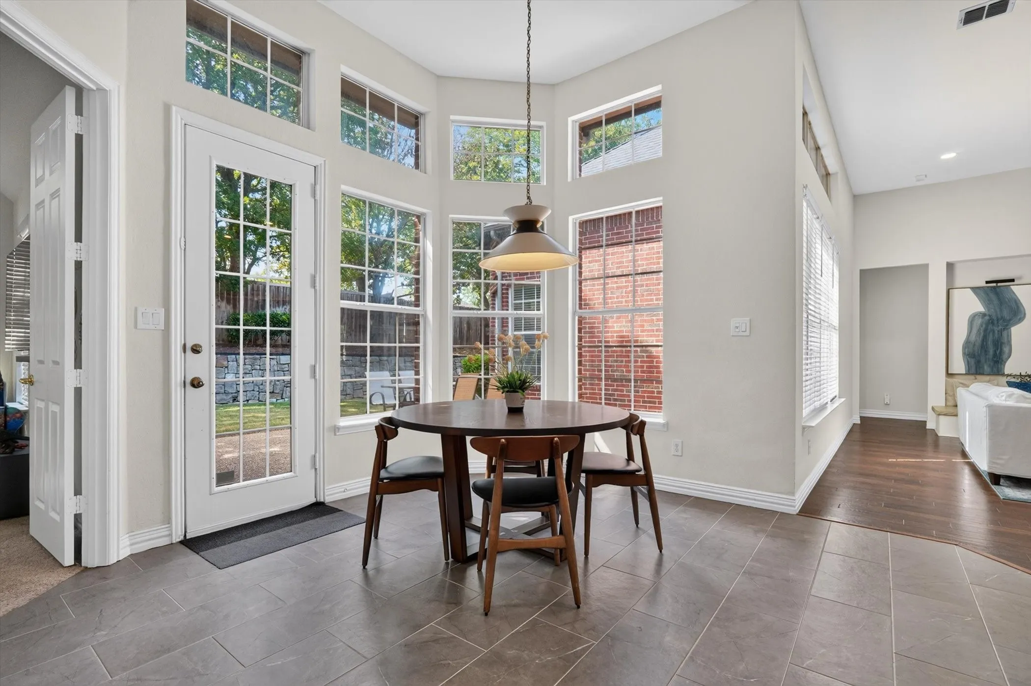 Dining area featuring a prominent bay window with multiple panes and transom windows, a glass-paneled exterior door, and a high ceiling