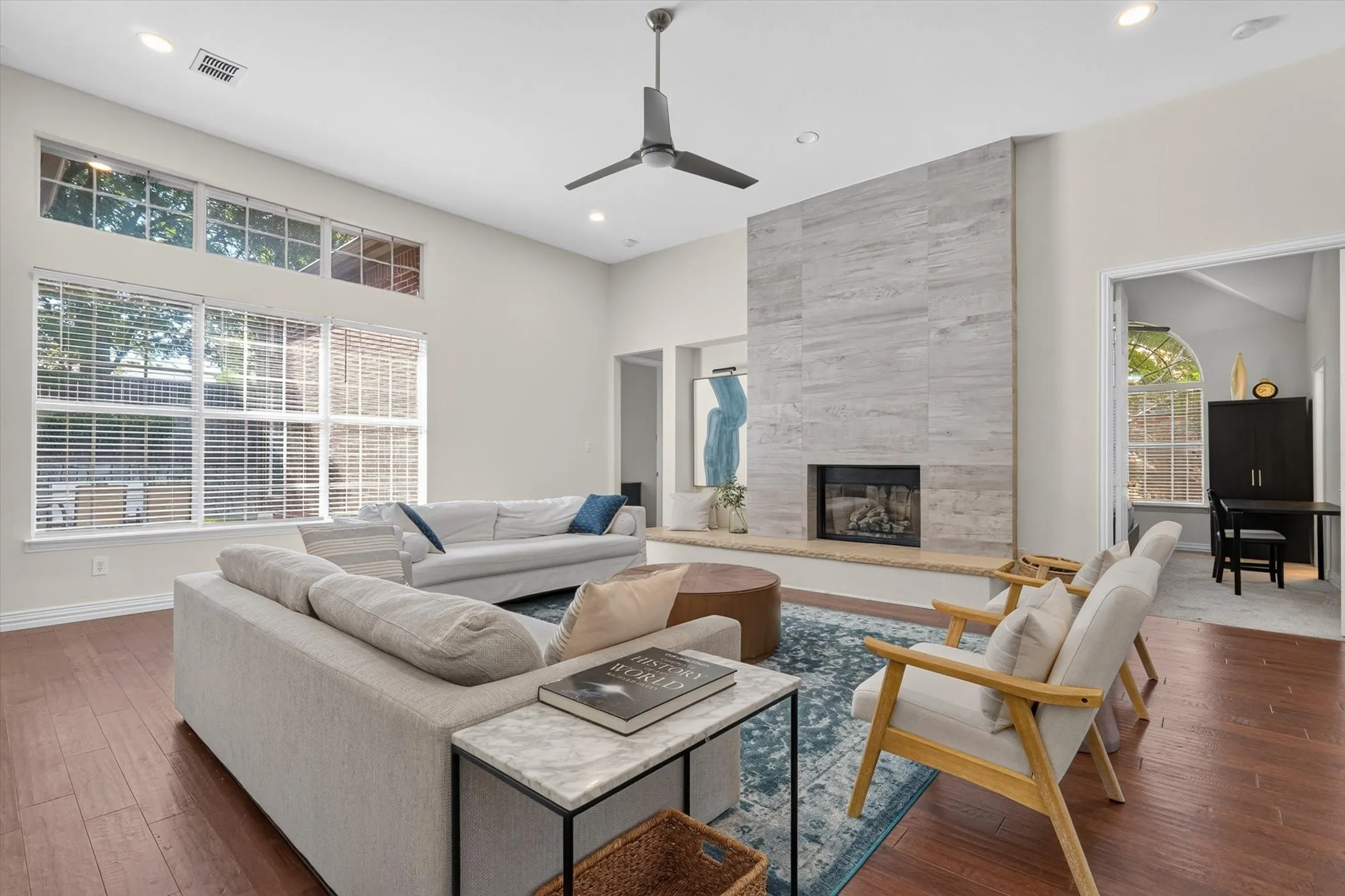 Spacious living area featuring a floor-to-ceiling fireplace with stone-look tile surround and hearth, vaulted ceiling, and recessed lighting