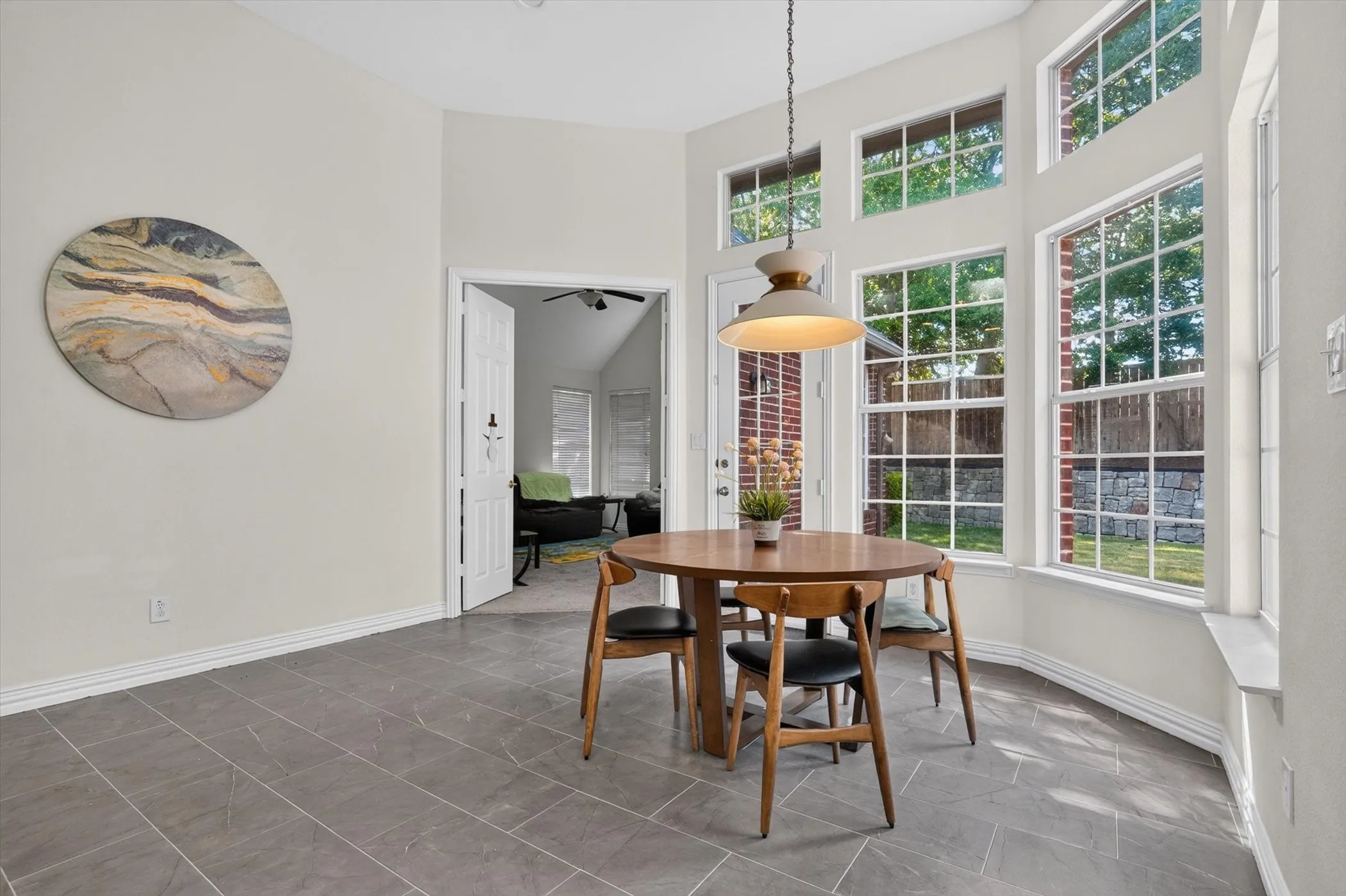Dining area featuring multiple windows, a high vaulted ceiling, grey tile flooring, and a contemporary pendant light fixture