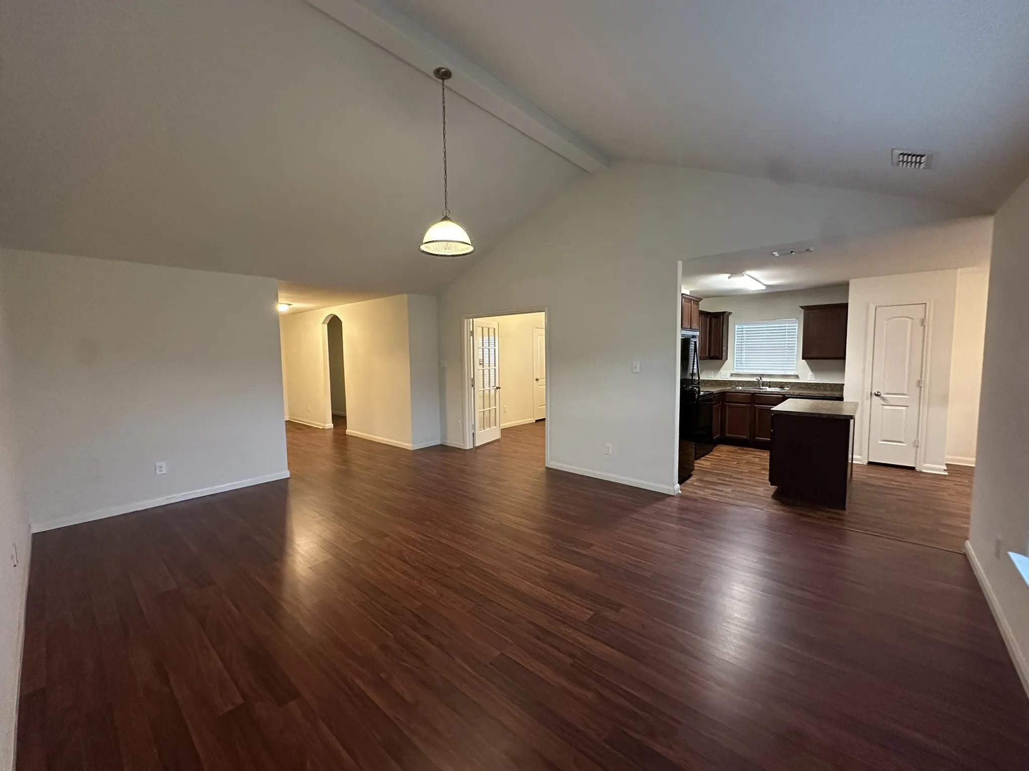 Expansive main living area featuring vaulted ceilings, wood-finish flooring, and an open concept layout