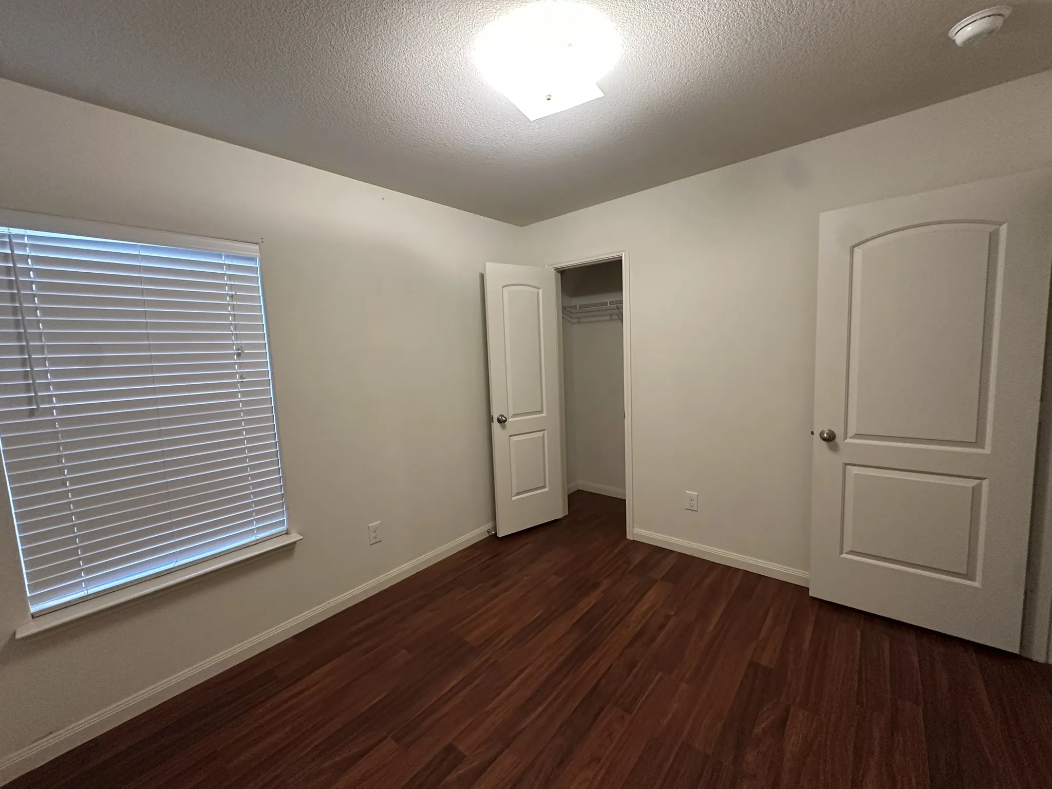 Room featuring wood-finish flooring, neutral wall tones, and white trim