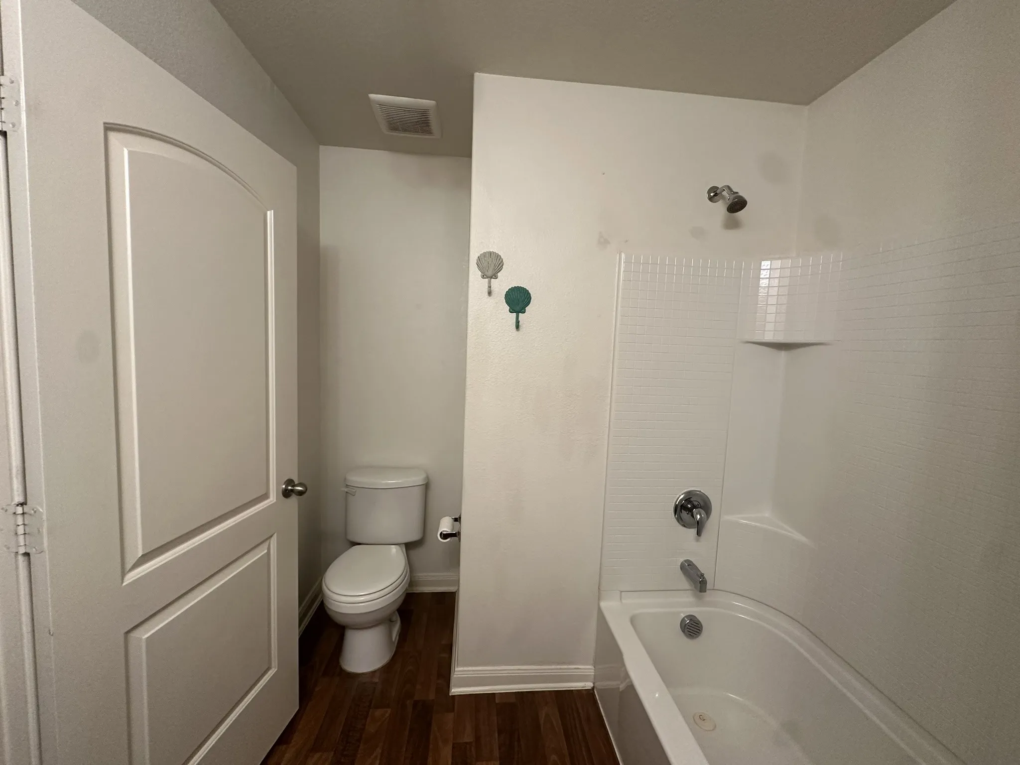 Bathroom featuring a white bathtub and shower combination, chrome fixtures, and a white toilet