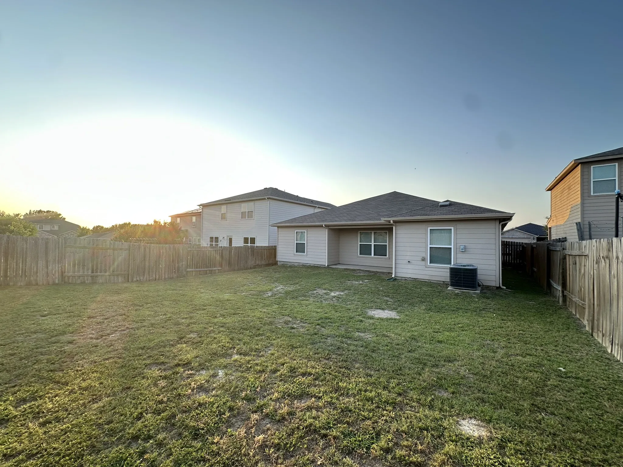 Expansive backyard featuring a wood fence perimeter and a central air conditioning unit