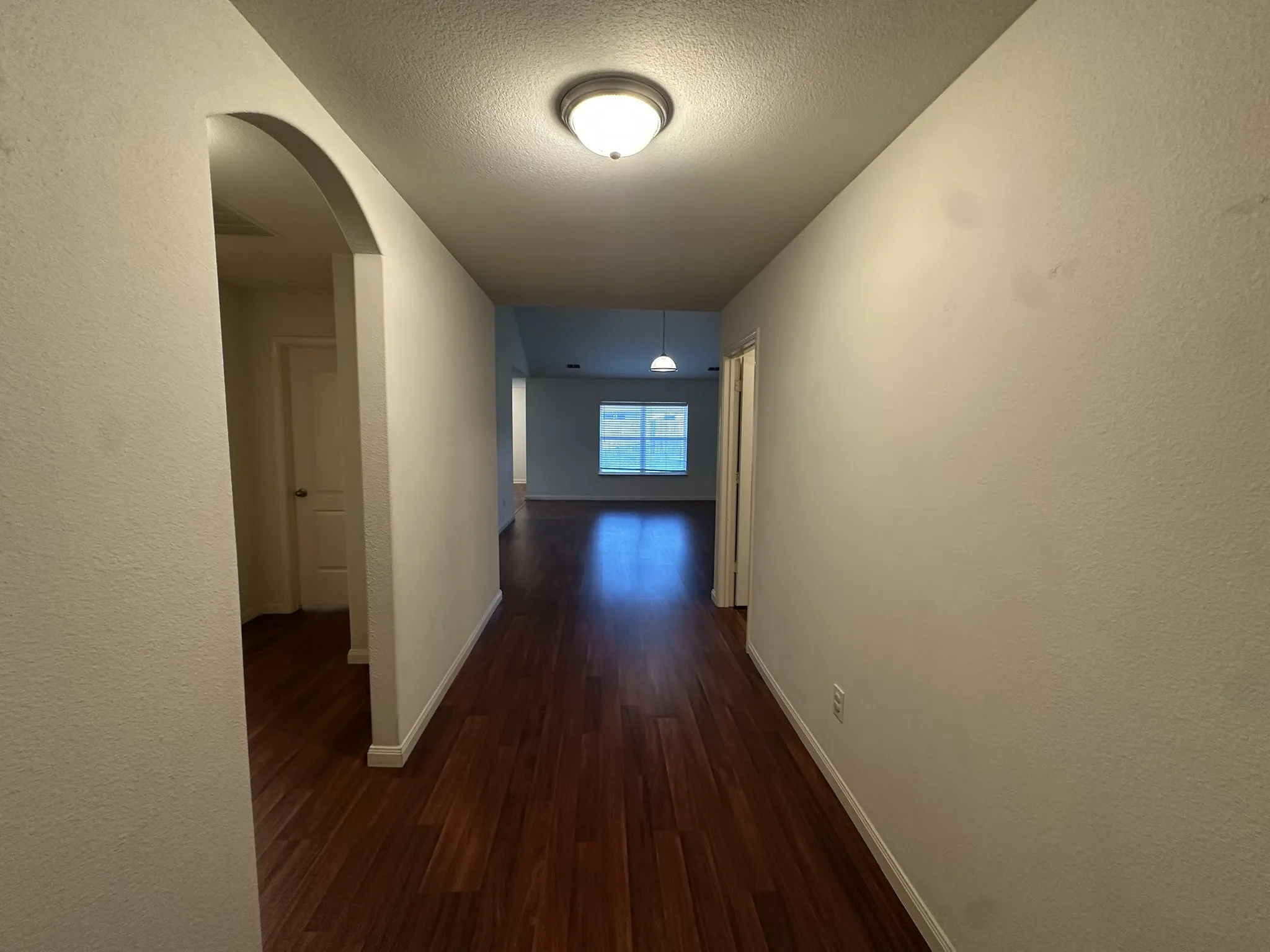 Hallway featuring wood-finish flooring, white baseboards, and a flush-mount ceiling light