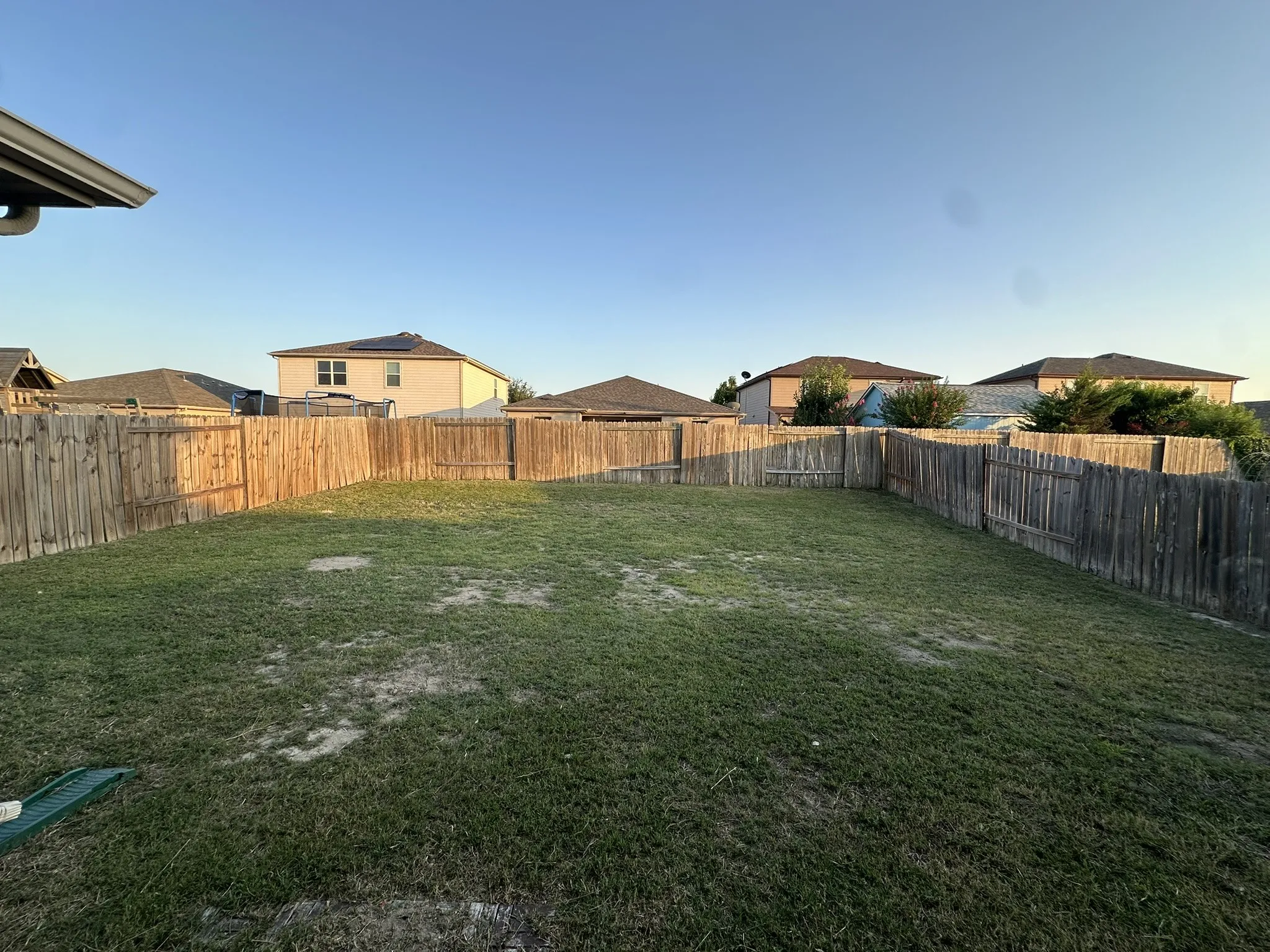 Expansive backyard featuring a full perimeter wood privacy fence and a broad grass lawn
