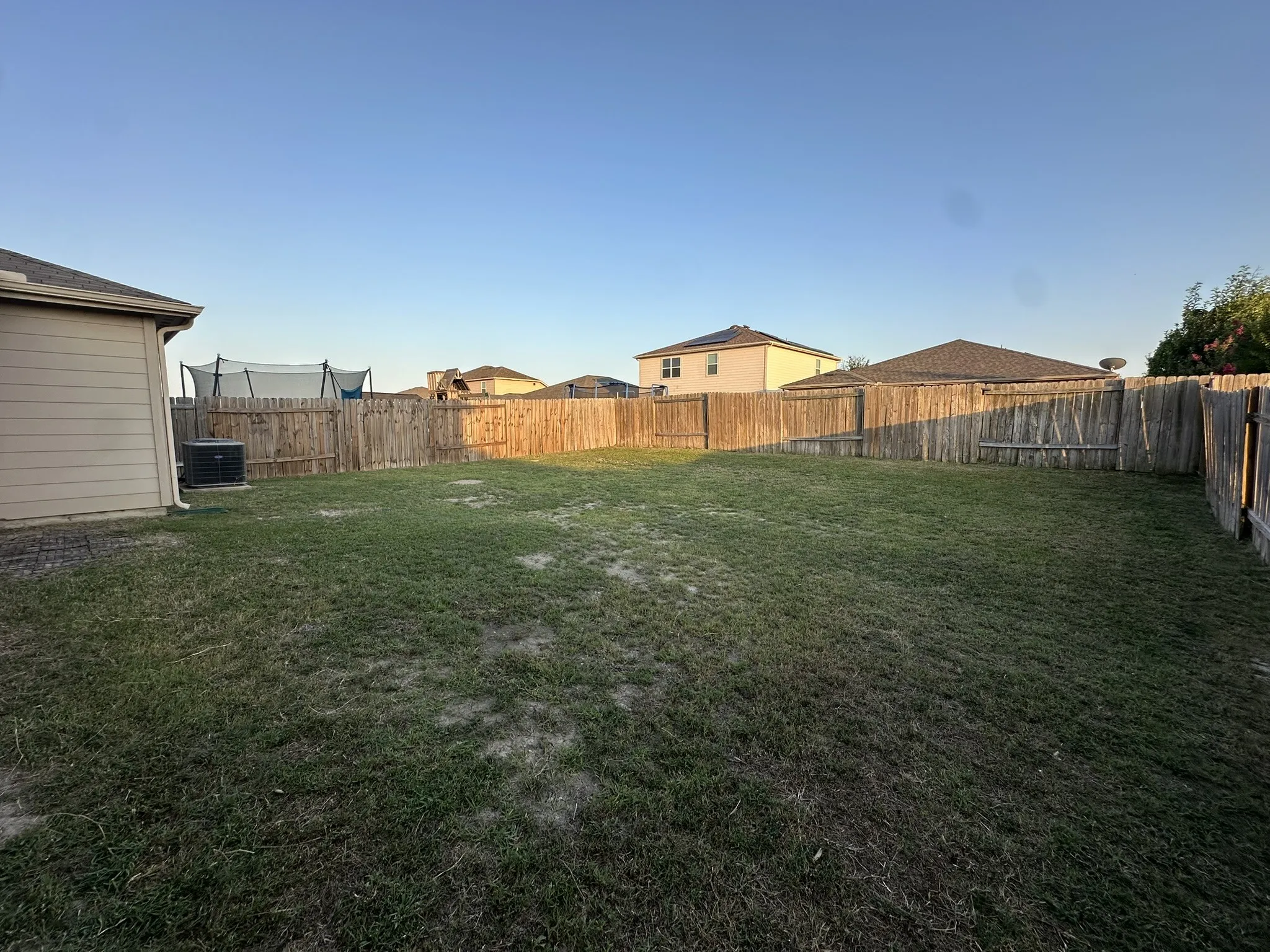 Expansive backyard with a full wood privacy fence and a tan siding exterior on the property